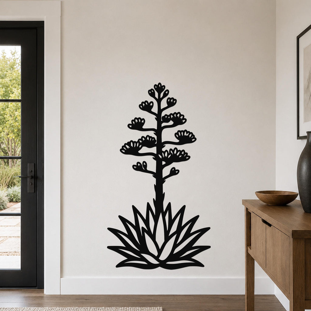 Black metal agave wall sculpture with blooming flower cutouts, mounted on a light-colored wall in a modern entryway.