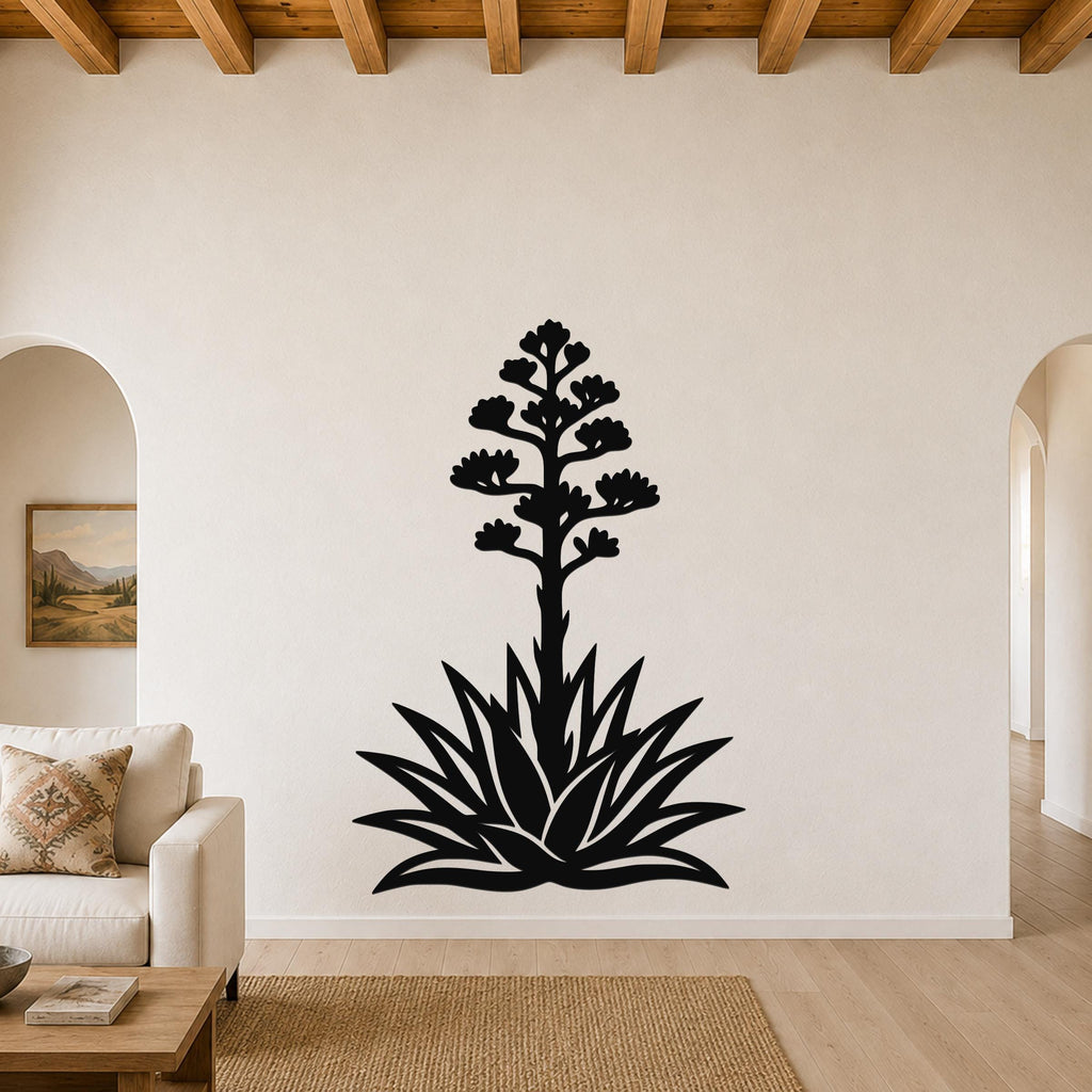 Black metal agave wall art with a blooming flower silhouette, mounted on a living room wall above a sofa.