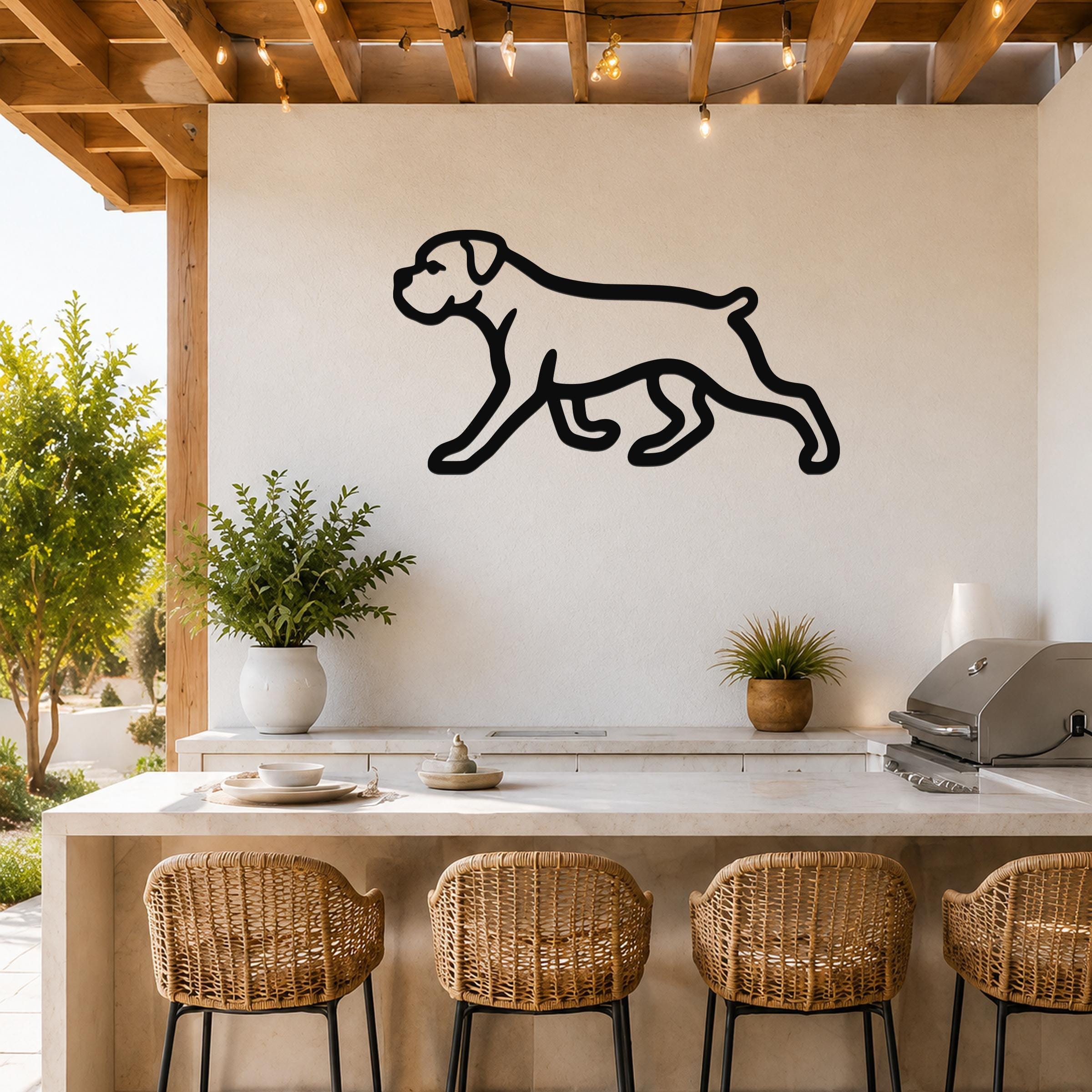 Black metal Boxer dog silhouette wall art mounted on a white outdoor wall above a kitchen counter with wicker bar stools.