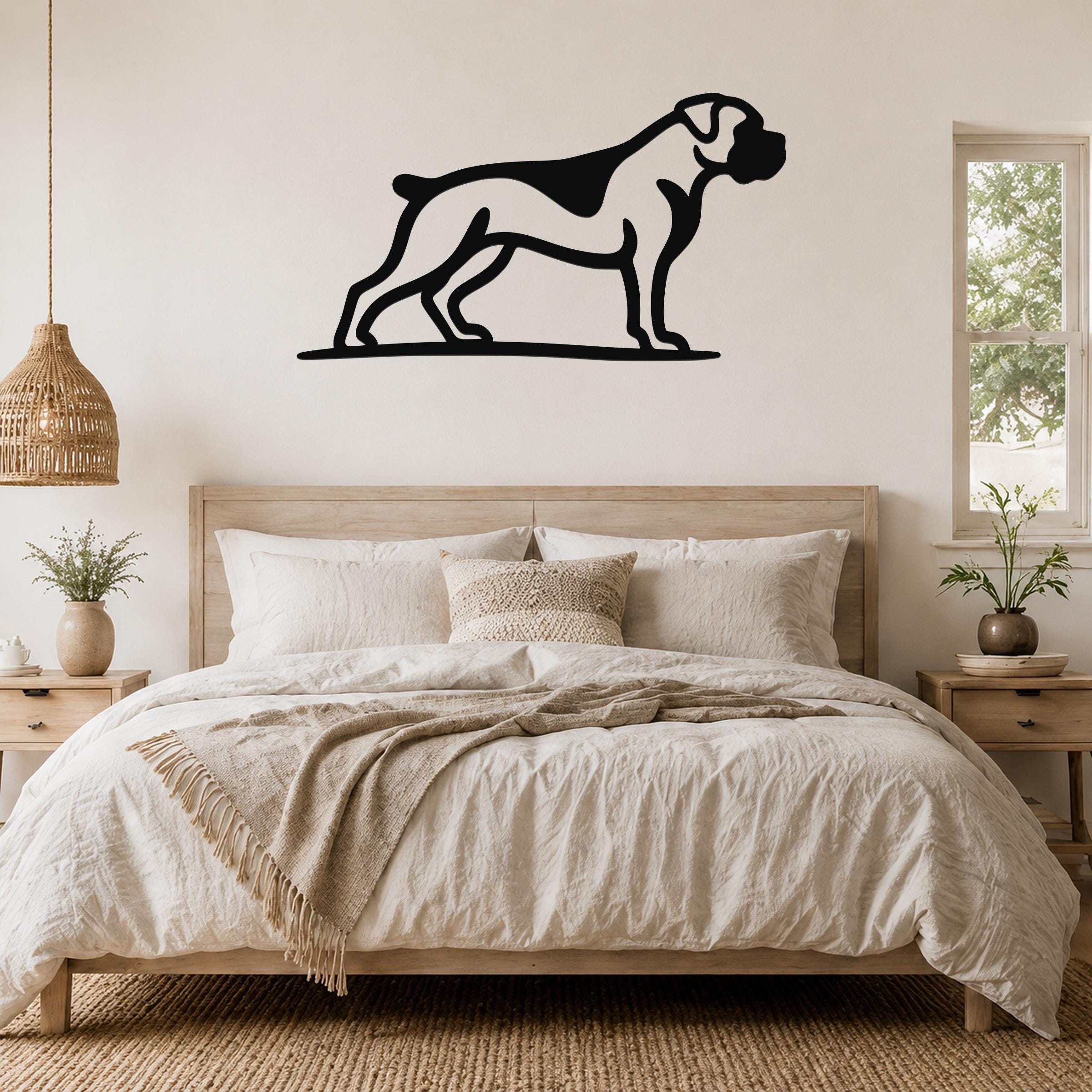 Black metal Boxer dog wall art silhouette mounted above a wooden bed in a neutral bedroom.