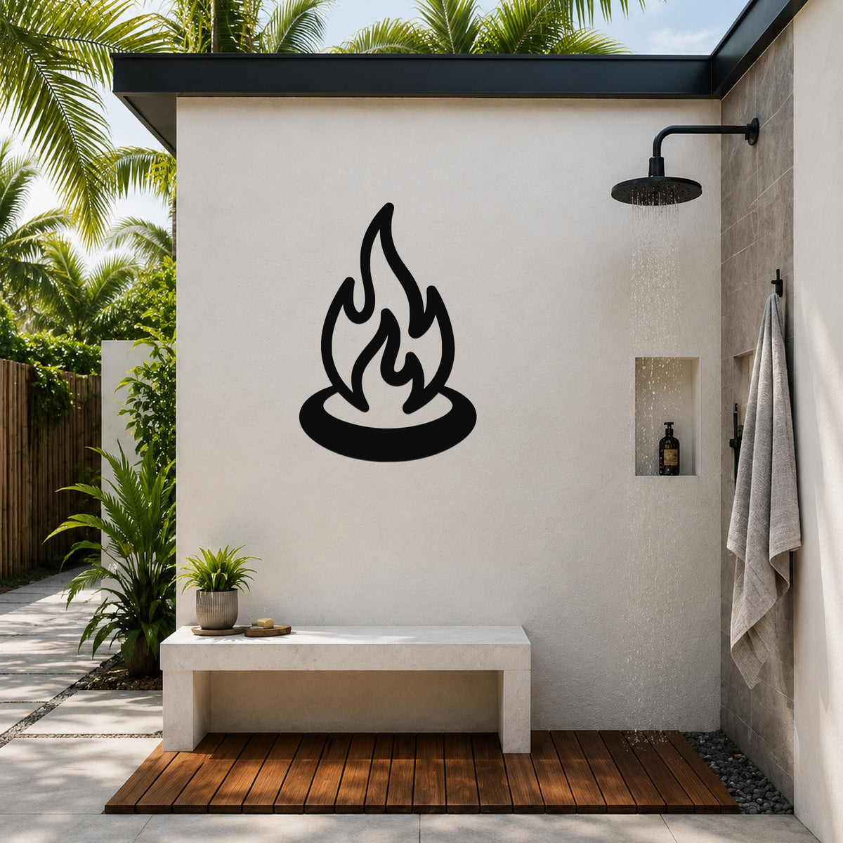 Black metal campfire wall art with flame and ring silhouette, mounted on a white outdoor shower wall above a concrete bench.