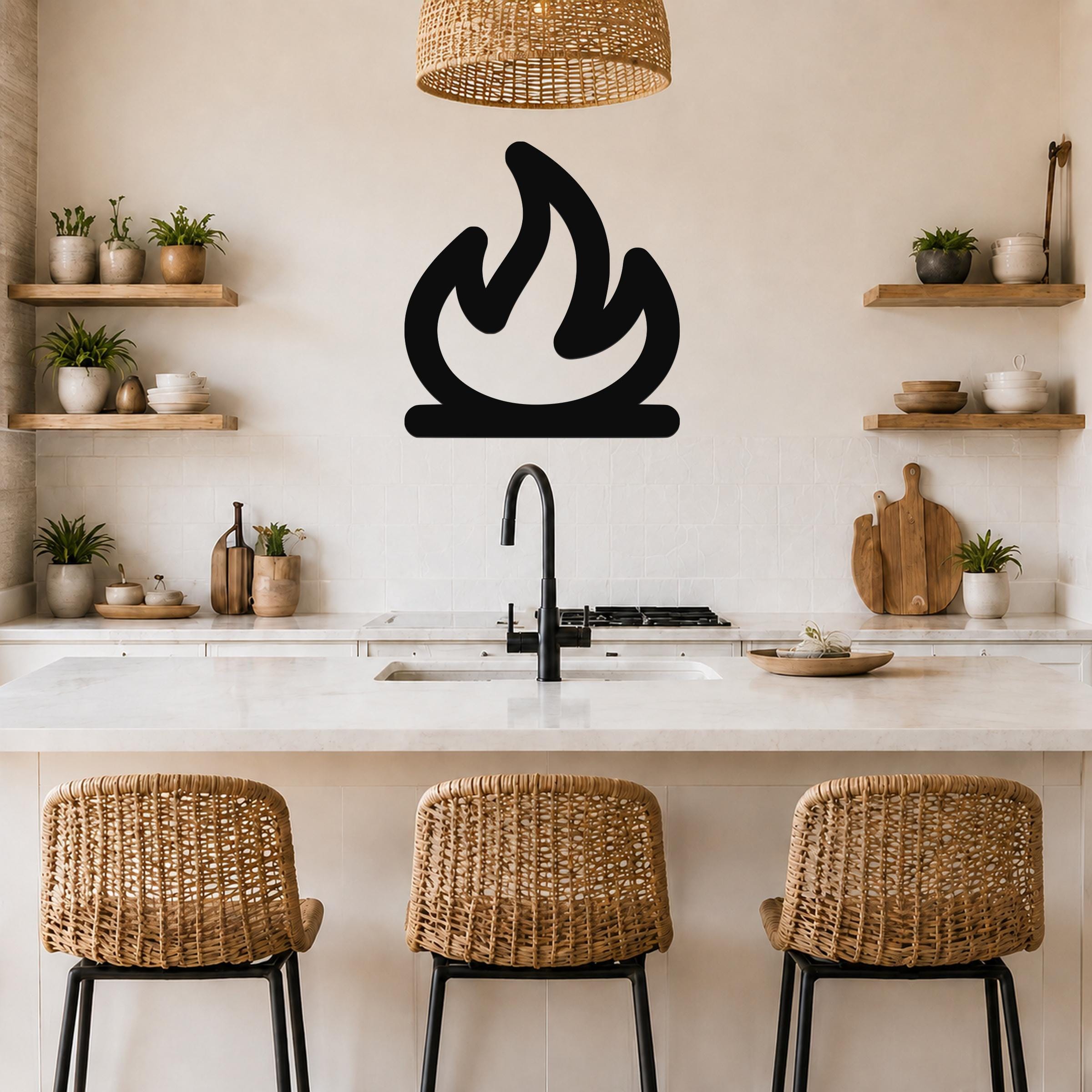 Black metal campfire silhouette wall art mounted on a kitchen wall above a counter, with a wicker pendant light and wooden shelves visible.