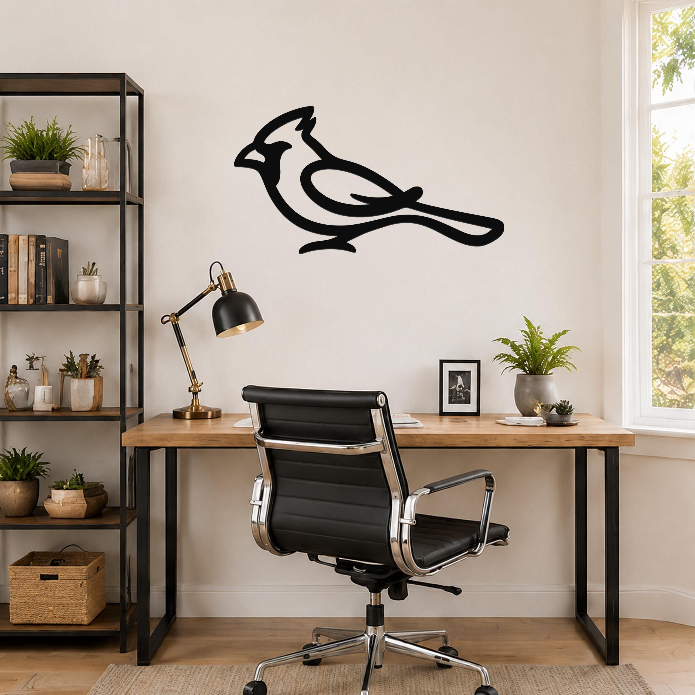 Black metal cardinal wall art with a bold silhouette design, mounted on a wall above a wooden desk in a home office.