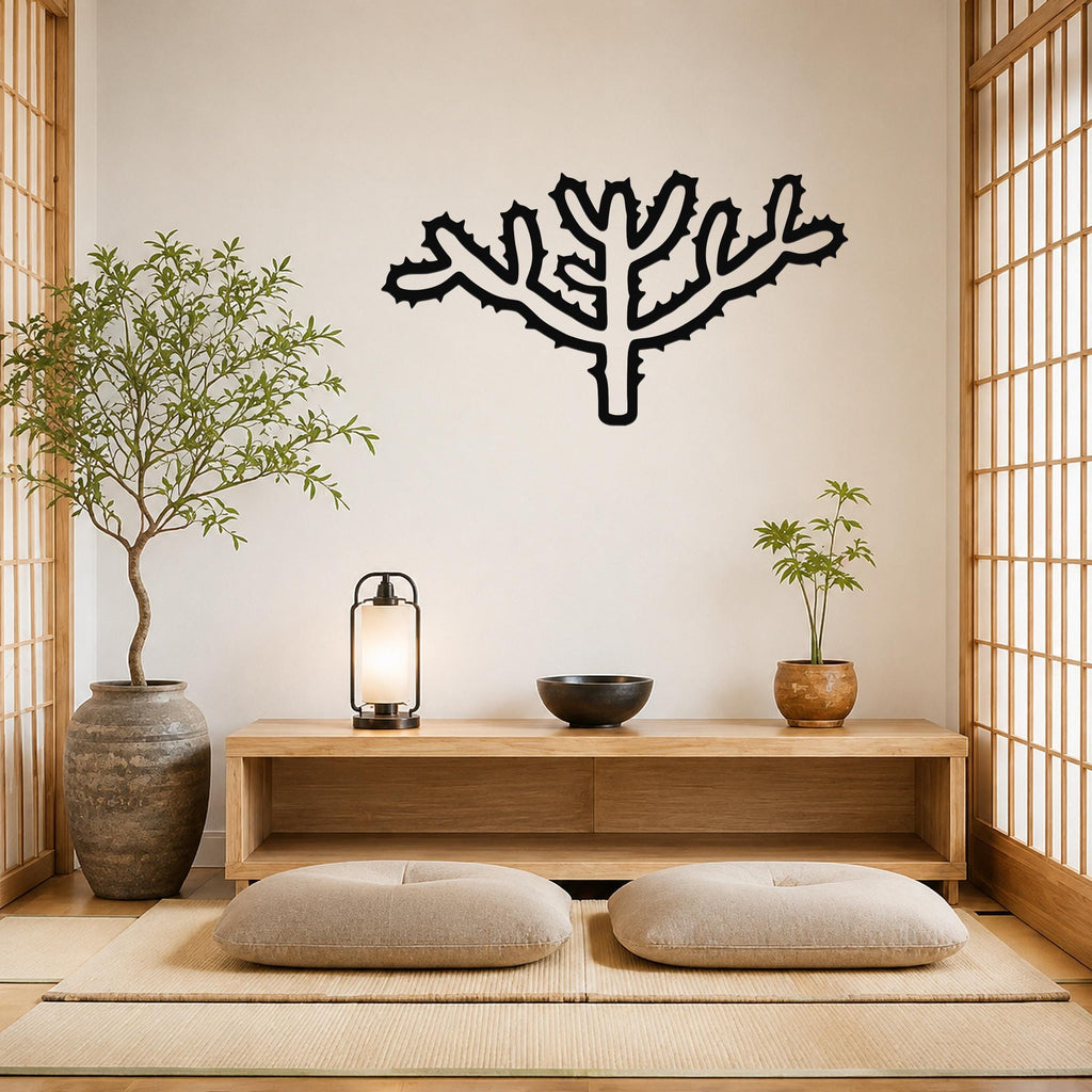 Black metal Cholla cactus wall art with spiky branch cutouts, mounted on a light wall above a wooden console in a minimalist room.