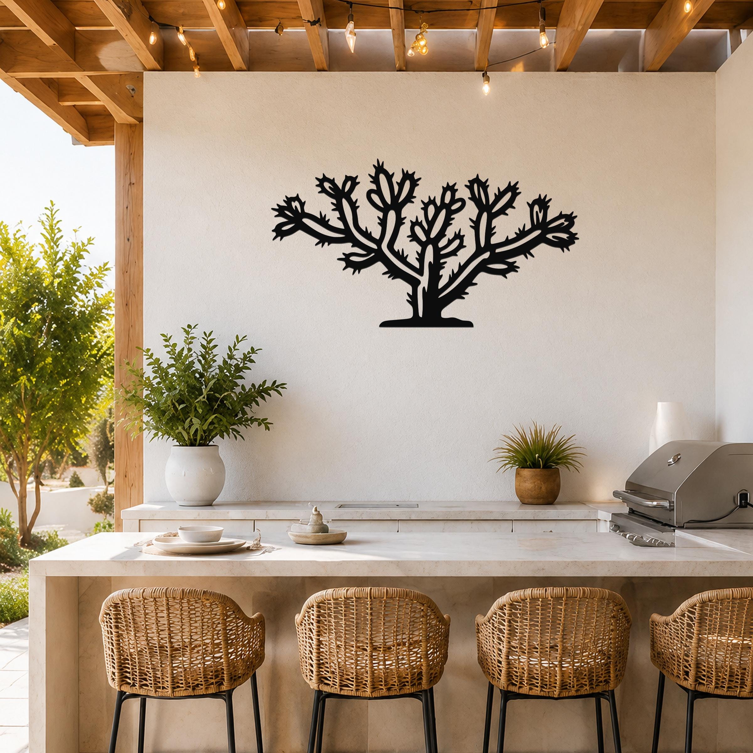 Black metal Cholla cactus wall art with branching silhouette and spines, mounted on a white wall above a kitchen counter in an outdoor patio setting.