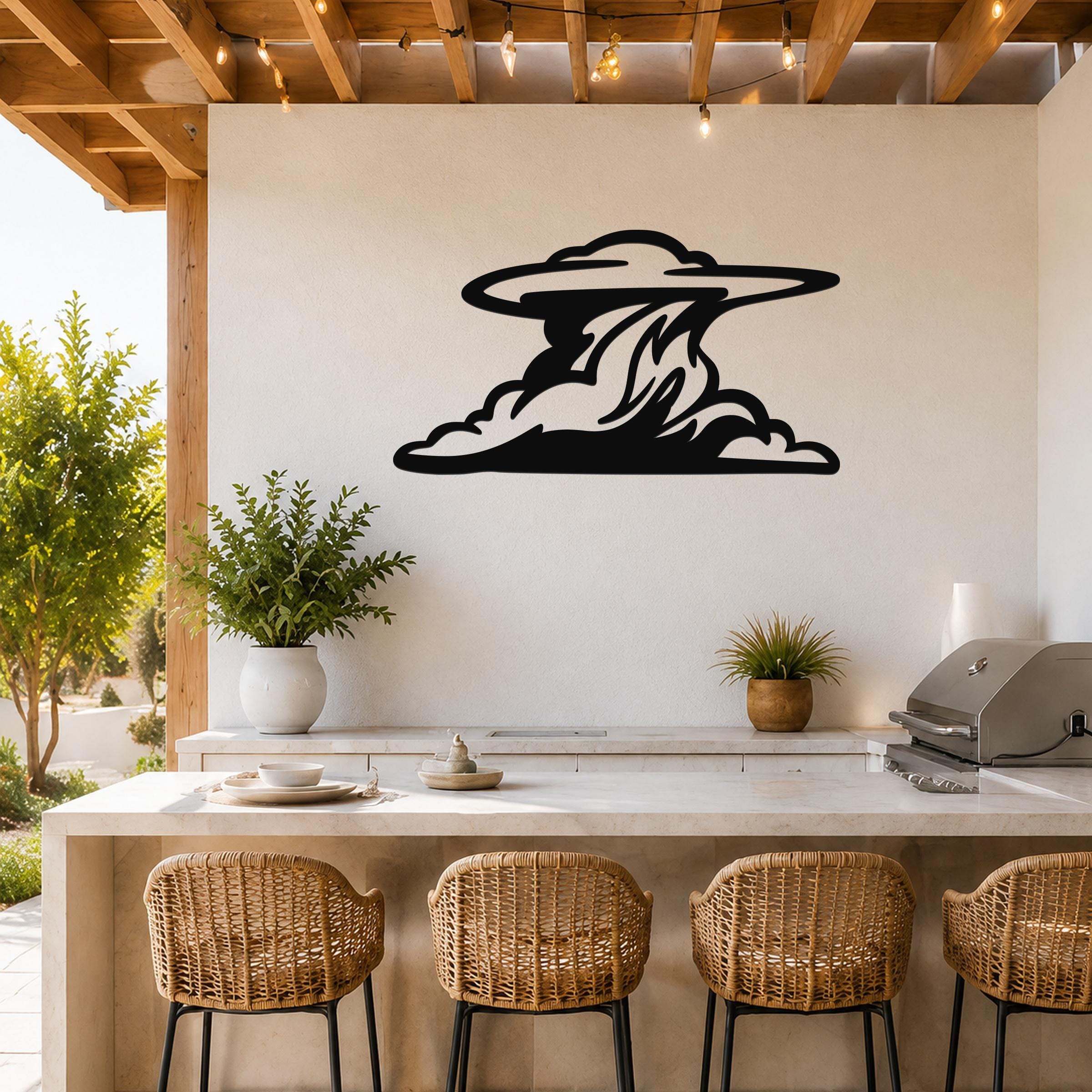 Black metal cloud wall art with flowing silhouette cutouts, mounted on a white wall above a kitchen counter in an outdoor patio setting.