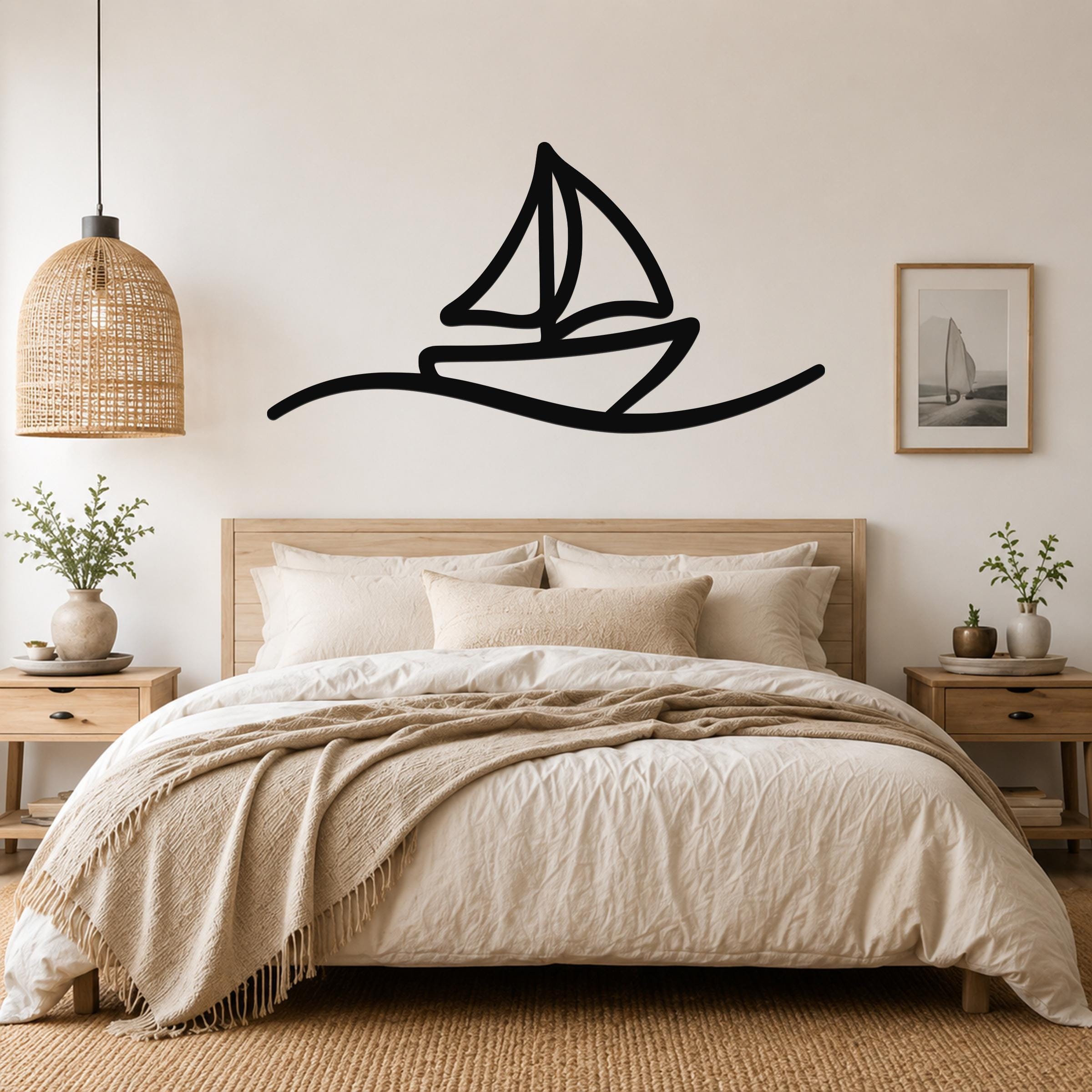 Black metal sailboat wall art with a silhouette design, mounted above a bed in a neutral bedroom.