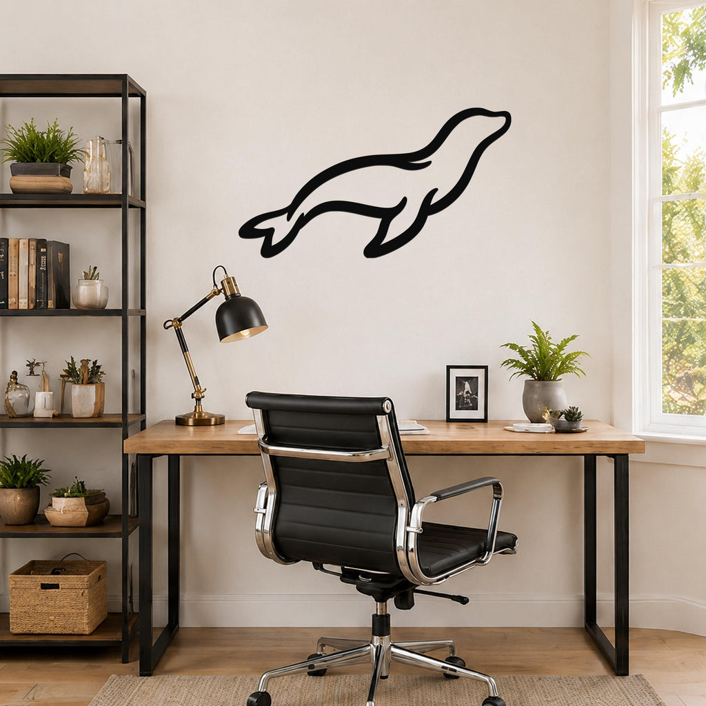 Black metal sea lion wall art with a sleek silhouette design, mounted on a wall above a wooden desk in a home office.