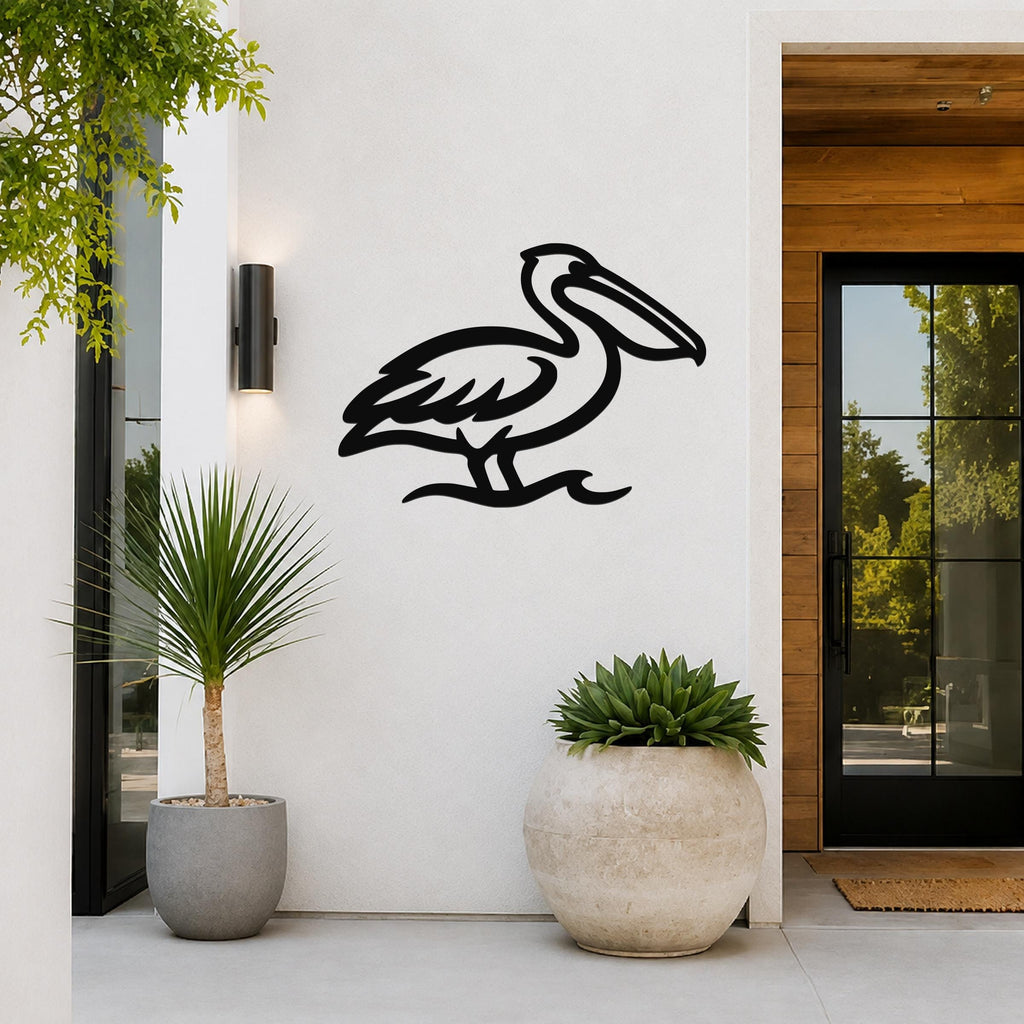 Black metal pelican wall art with a cutout silhouette, mounted on a white exterior wall beside a glass door and potted plants.