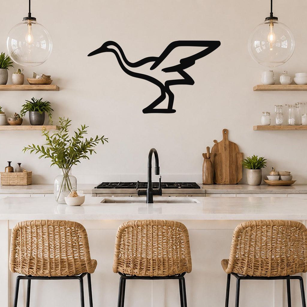 Black metal crane wall art silhouette mounted on a kitchen wall above a counter, with wicker bar stools and open shelves visible below.