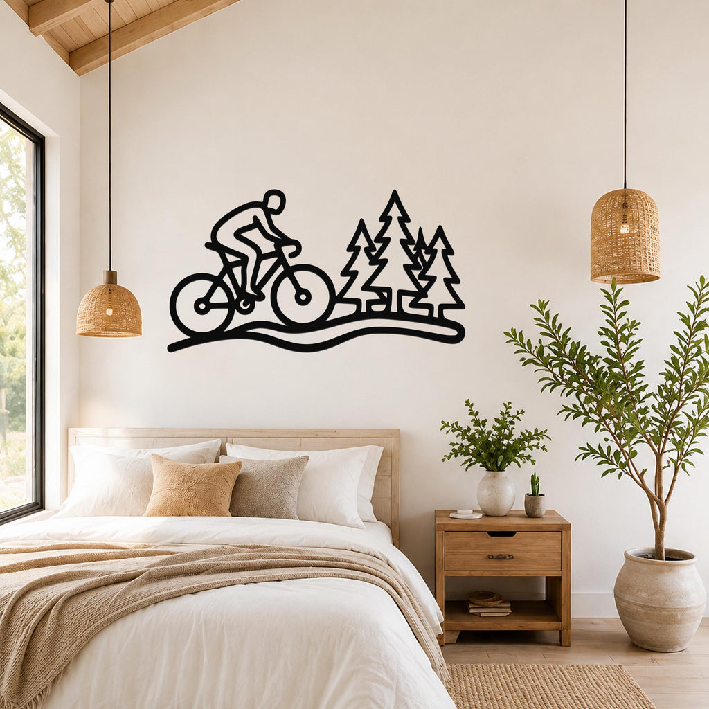 Black metal wall art silhouette of a cyclist on a trail with pine trees, mounted above a bed in a bedroom.