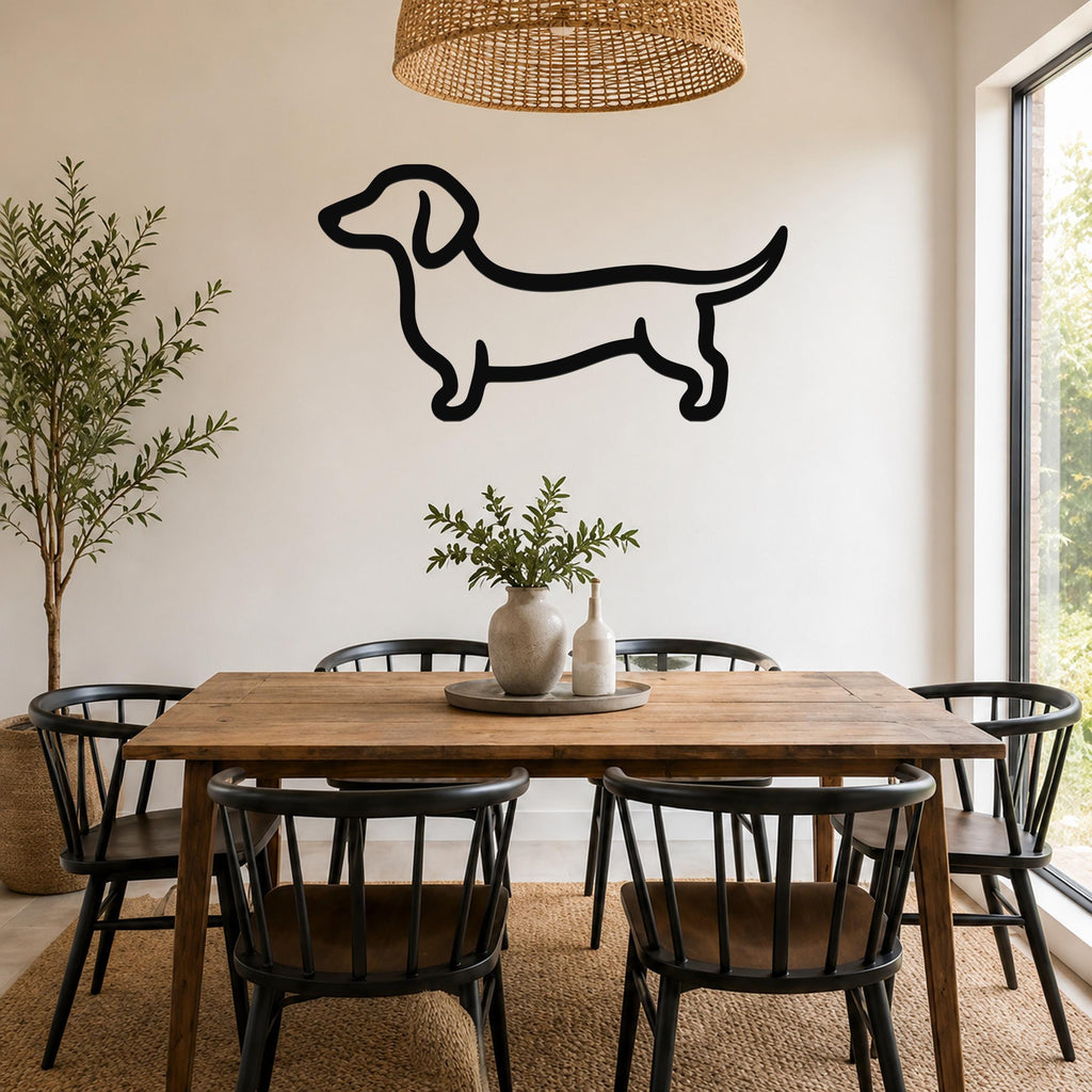 Black metal dachshund wall art silhouette mounted on a white wall above a wooden dining table in a bright dining room.