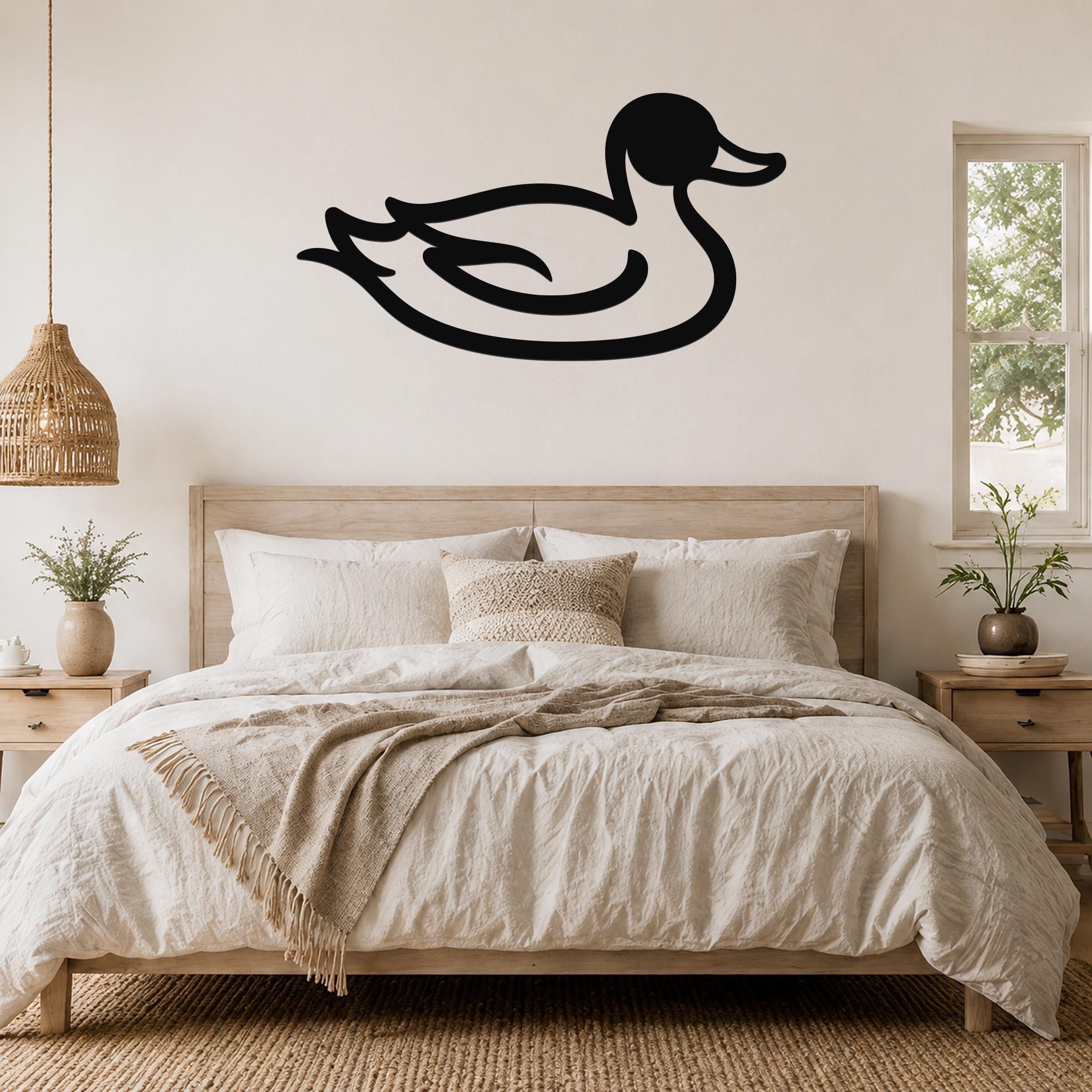 Black metal duck wall art silhouette mounted above a wooden bed in a neutral bedroom.