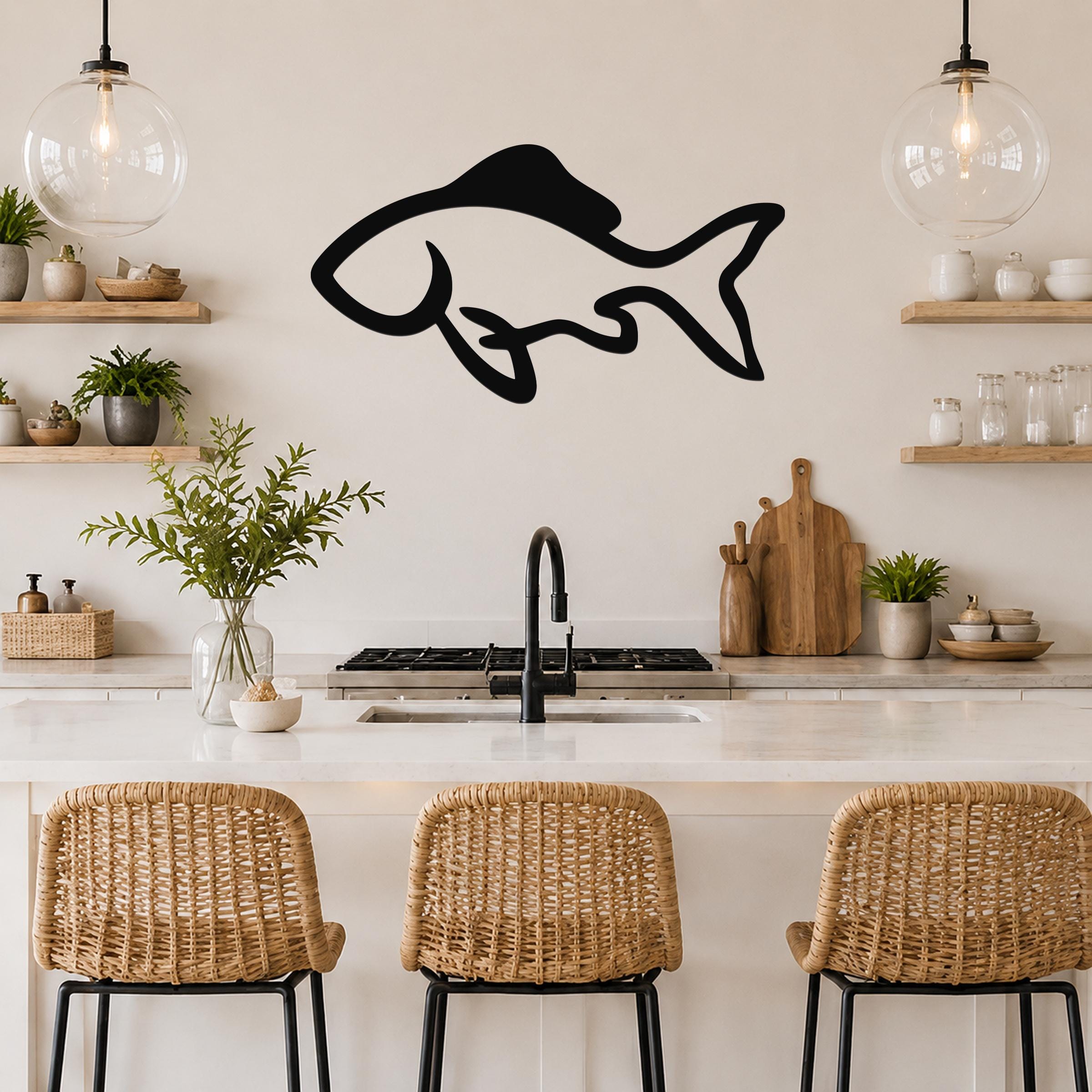 Black metal fish wall art with a graceful silhouette design, mounted on a kitchen wall above a counter.