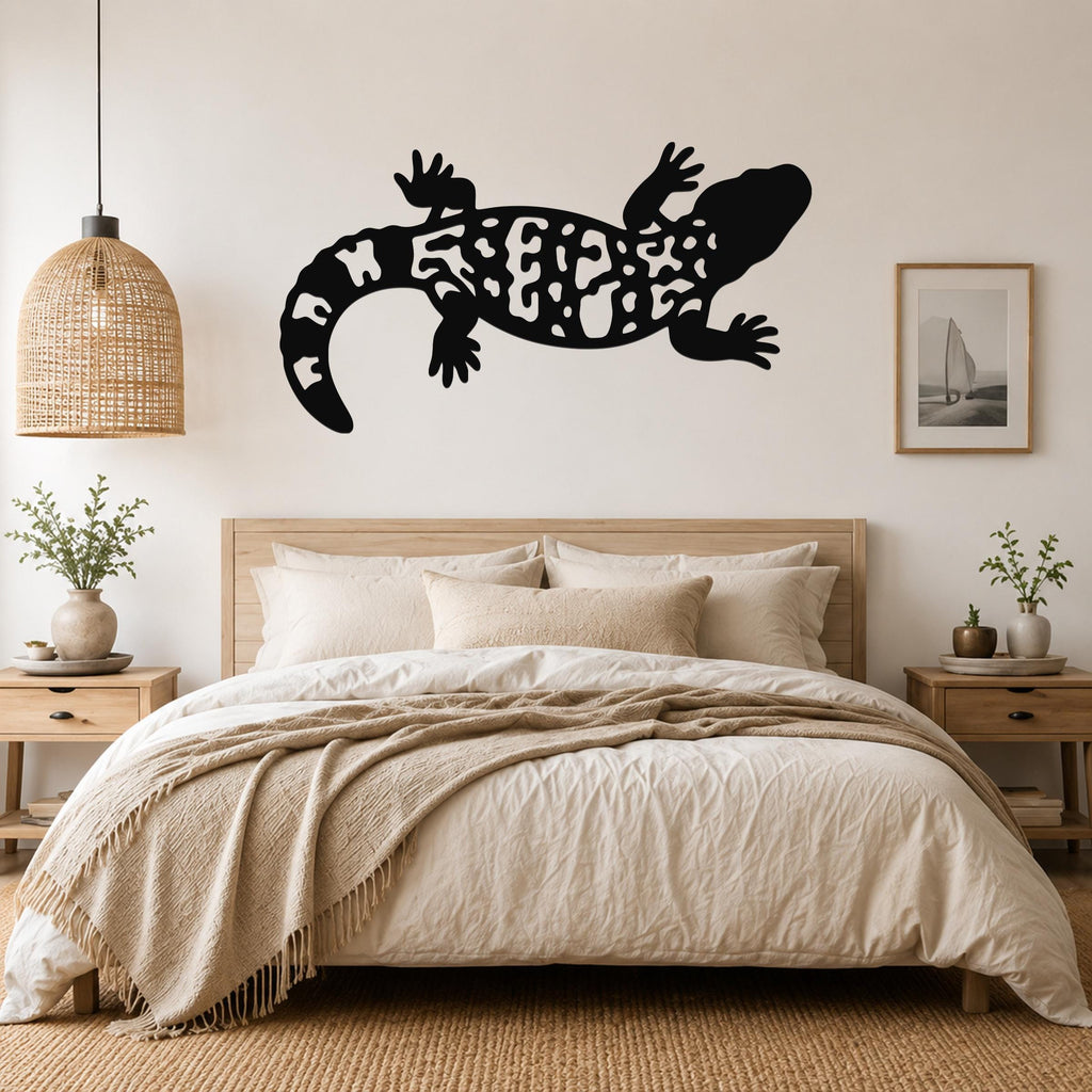 Black metal wall art of a Gila monster with intricate cutout patterns, mounted above a bed in a neutral bedroom.