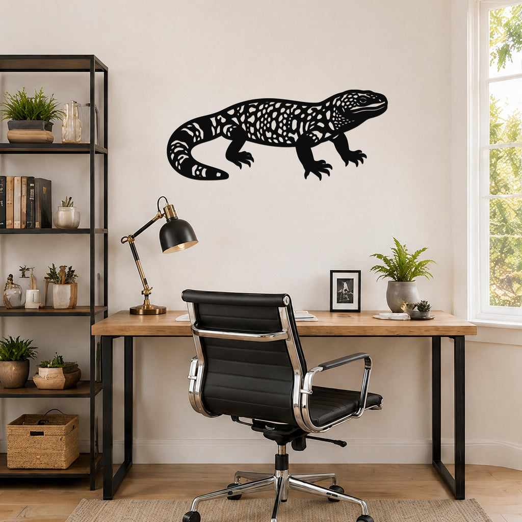 Black metal Gila monster wall art with intricate cutout patterns, mounted on a wall above a wooden desk in a home office.