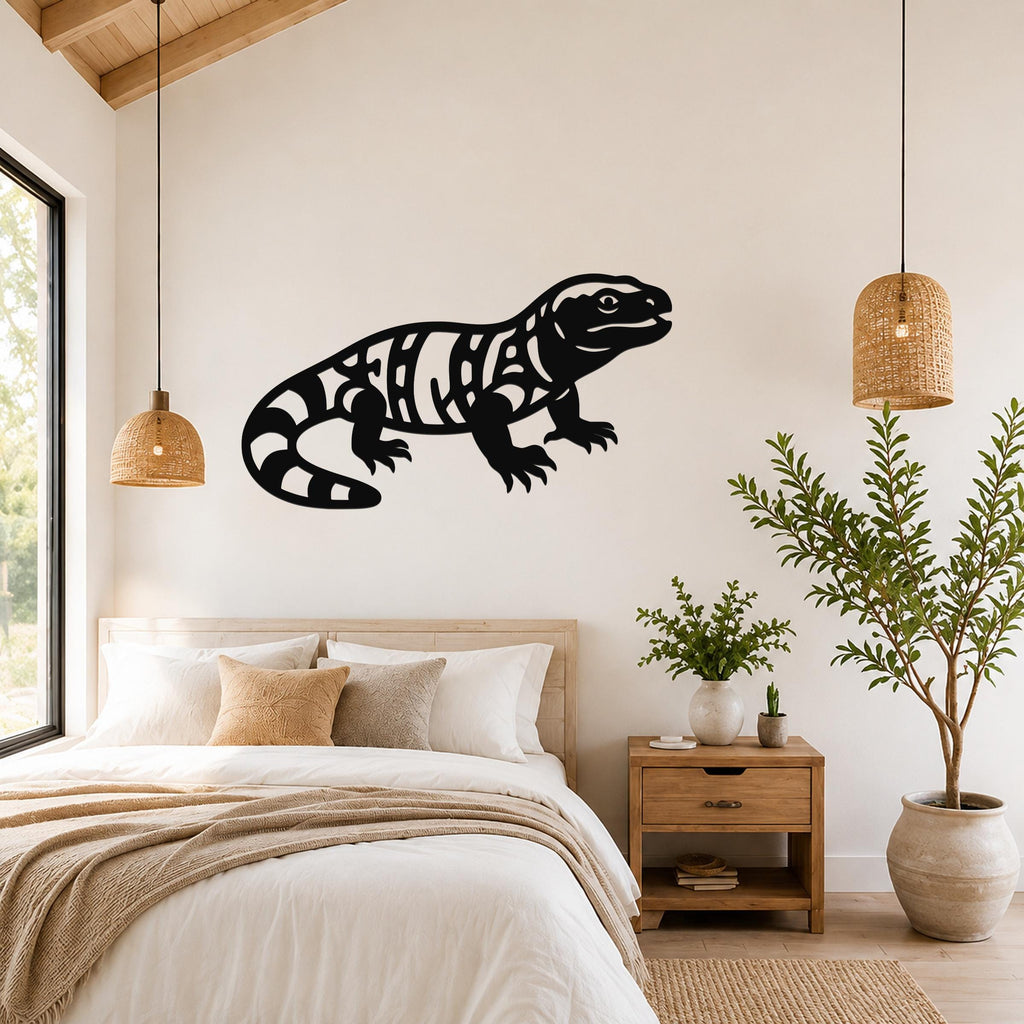 Black metal Gila monster wall art with intricate internal cutouts, mounted on a bedroom wall above a bed.