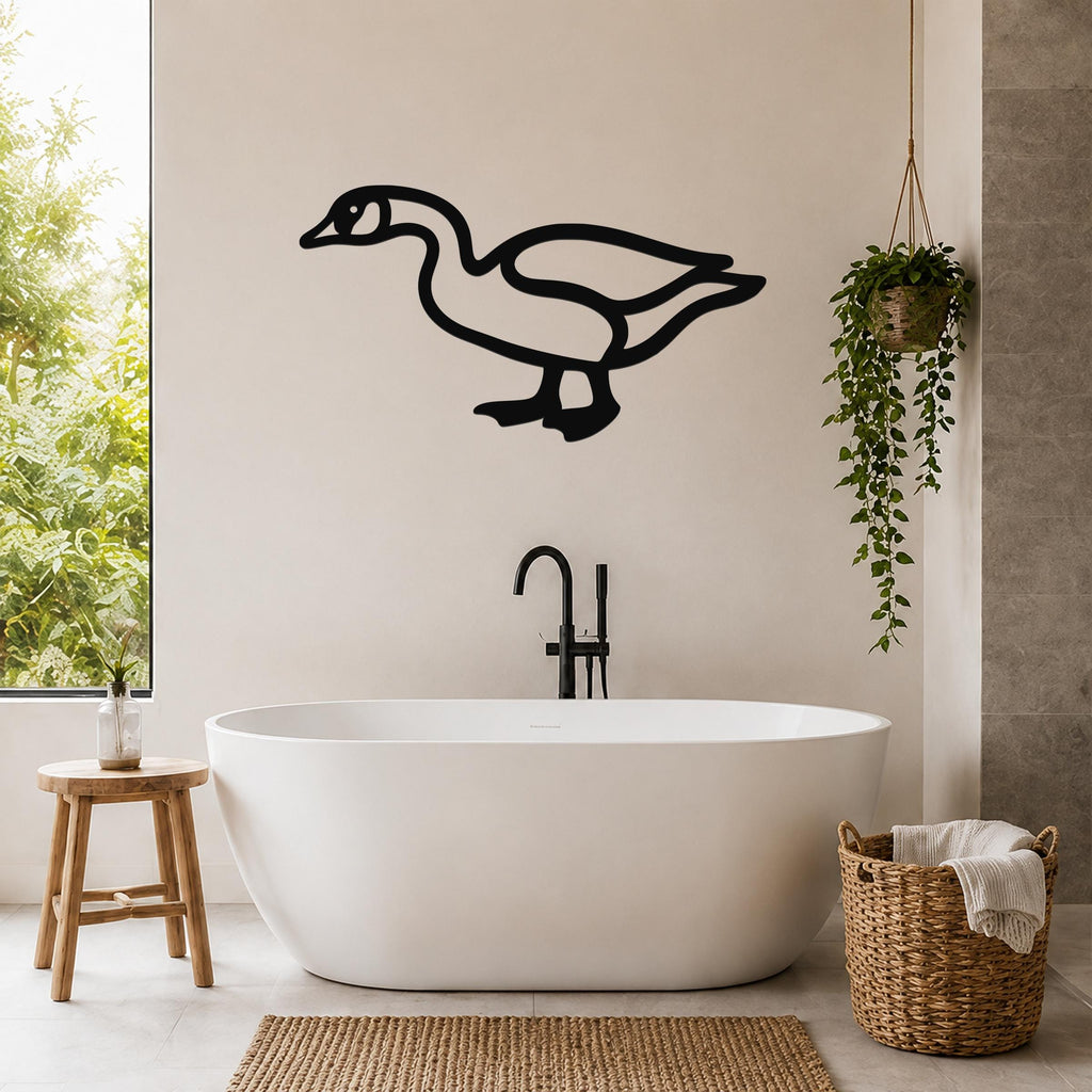 Black metal goose wall art silhouette mounted on a bathroom wall above a freestanding tub, with a hanging plant and woven basket nearby.