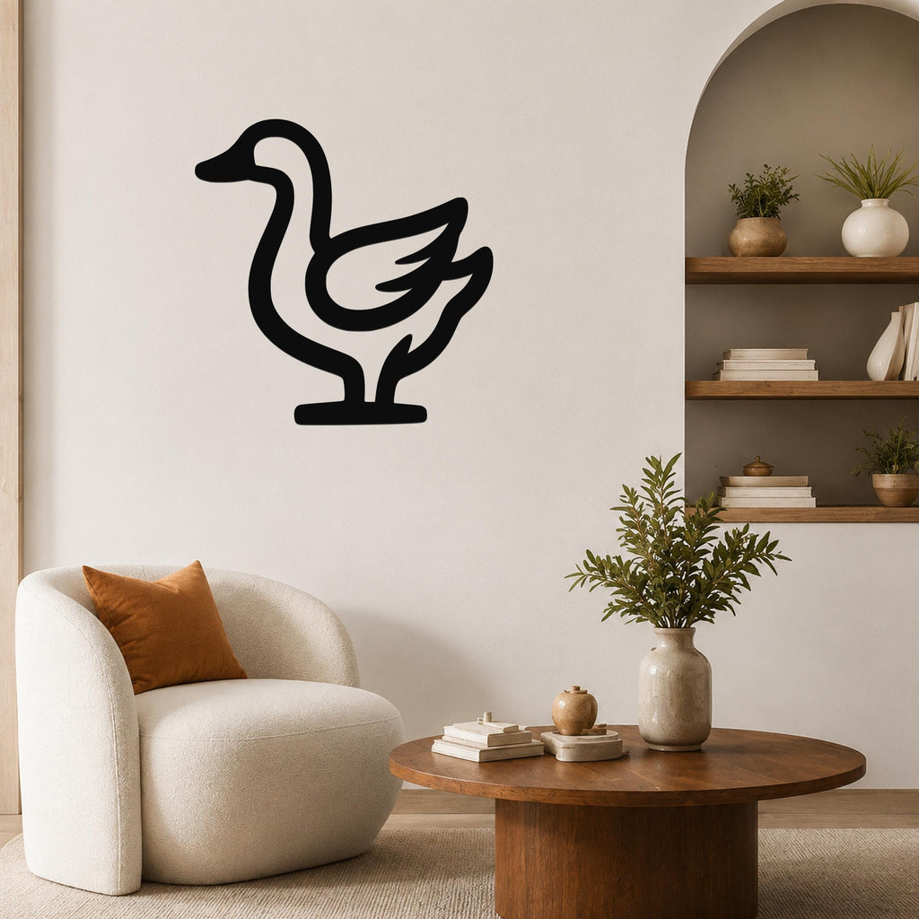 Black metal goose wall art silhouette mounted on a living room wall above a white armchair.