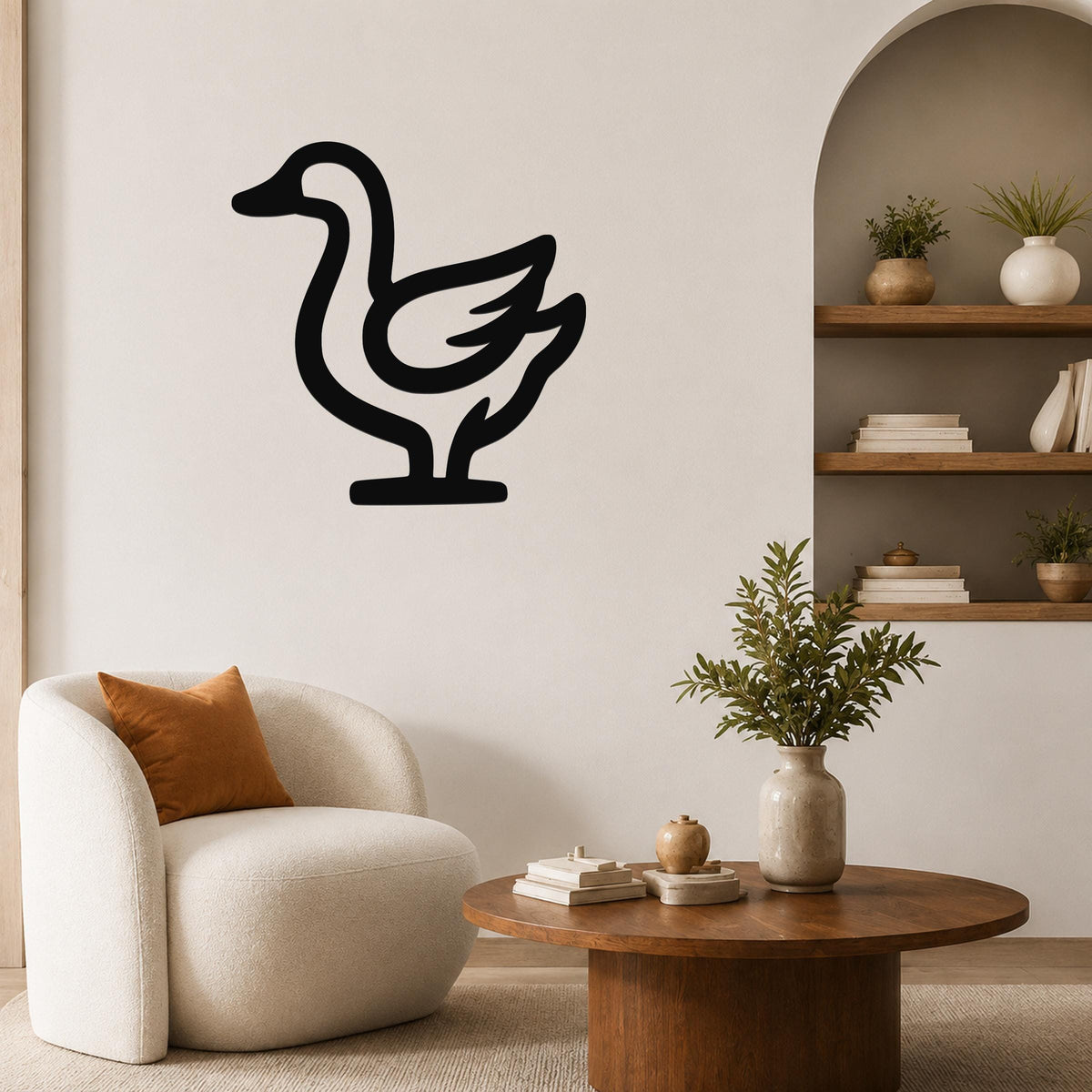 Black metal goose wall art silhouette mounted on a living room wall above a white armchair.