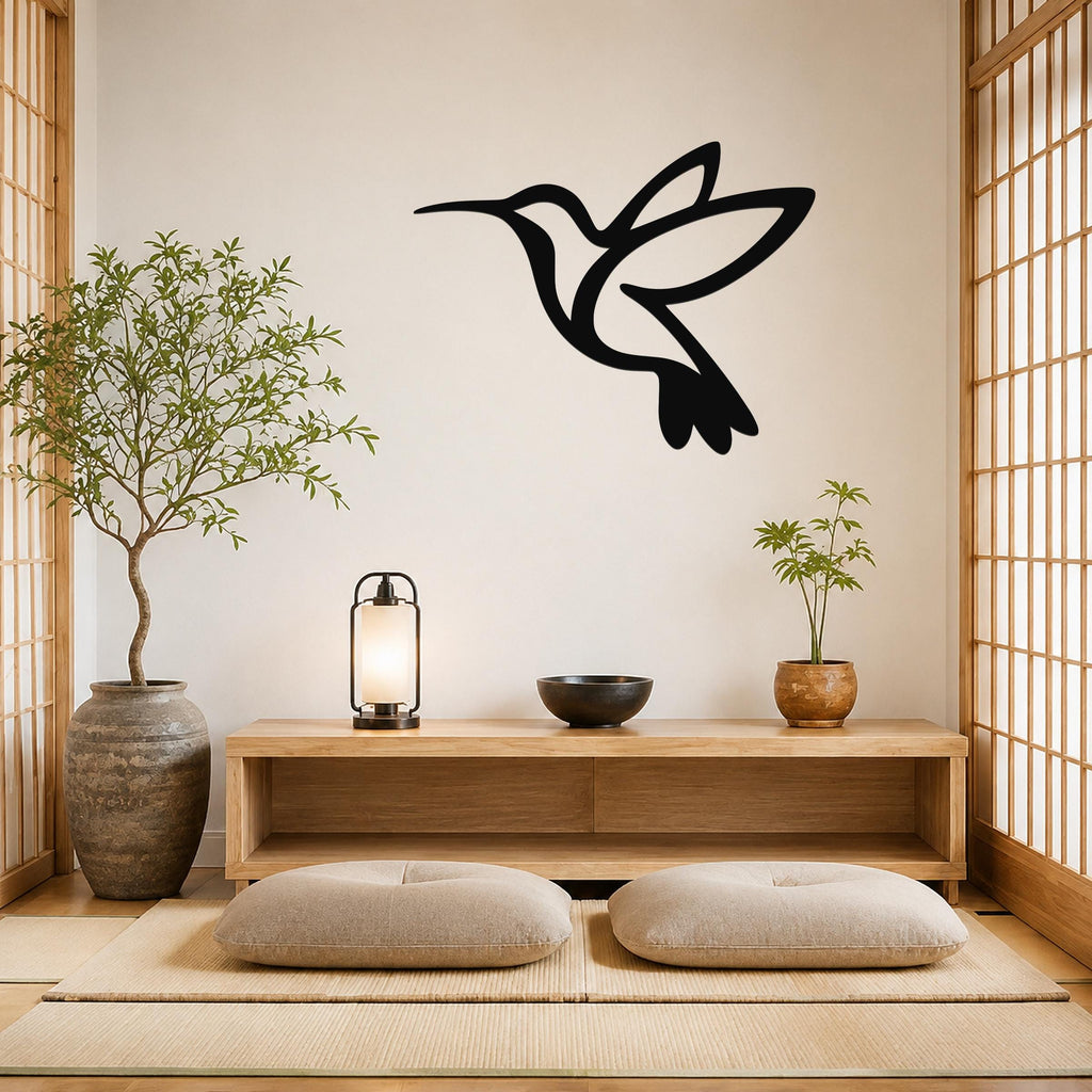Black metal hummingbird wall art with a silhouette cutout design, mounted on a wall above a wooden console in a minimalist room.