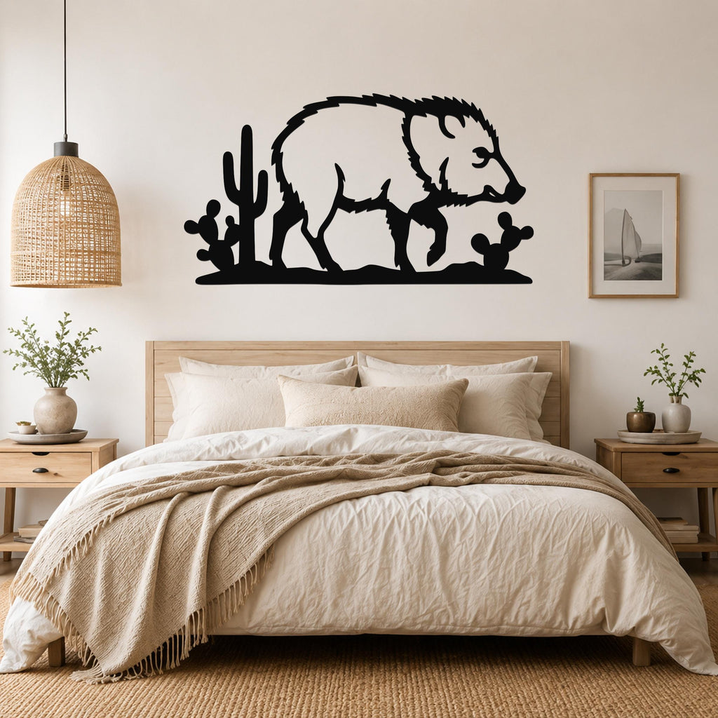 Black metal wall art silhouette of a javelina with cacti, mounted above a bed in a bedroom.