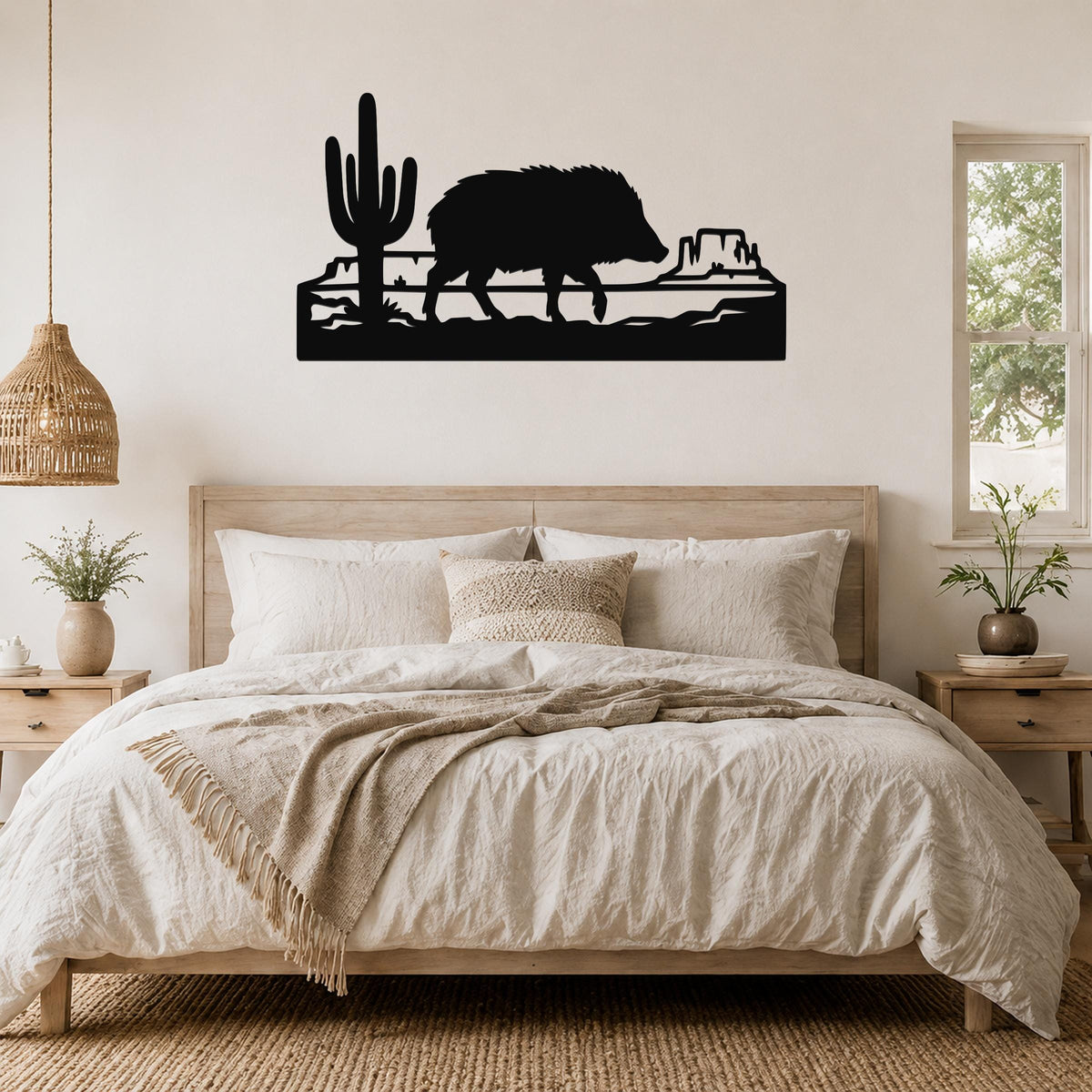 Black metal wall art silhouette of a javelina and cactus in a canyon scene, mounted above a bed in a bedroom.