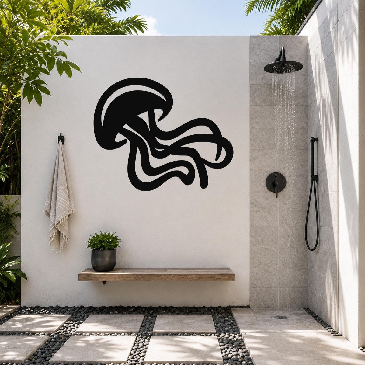 Black metal jellyfish wall art with flowing tentacle cutouts, mounted on a white outdoor shower wall above a wooden bench.