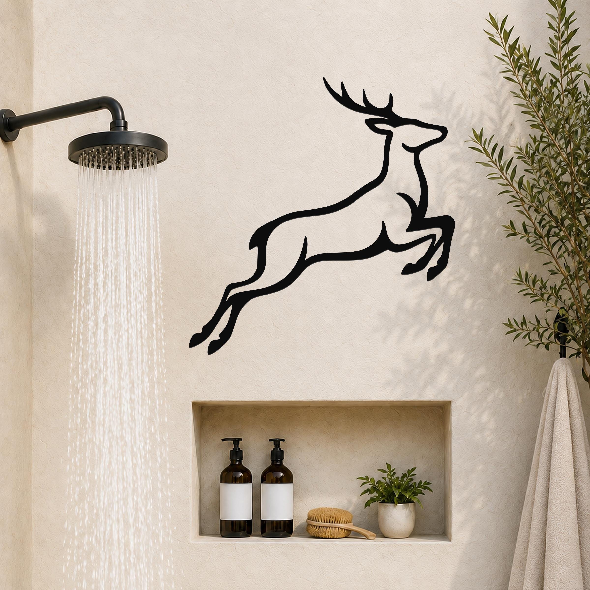 Black metal deer wall art with a leaping silhouette, mounted on a bathroom wall above a built-in shelf.