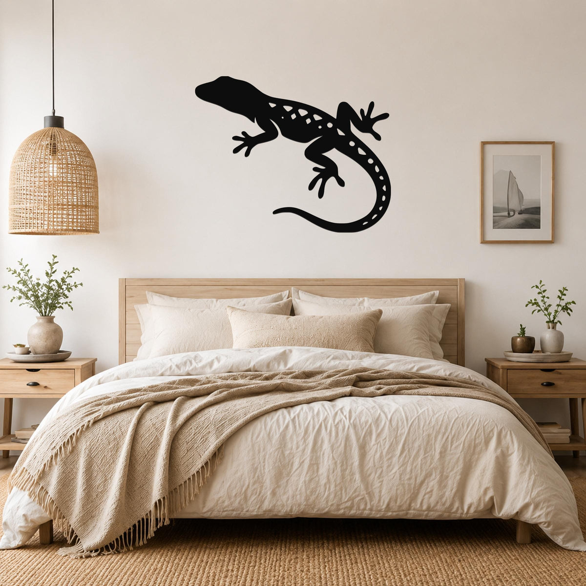 Black metal lizard wall art with internal cutout details, mounted above a bed in a neutral bedroom.