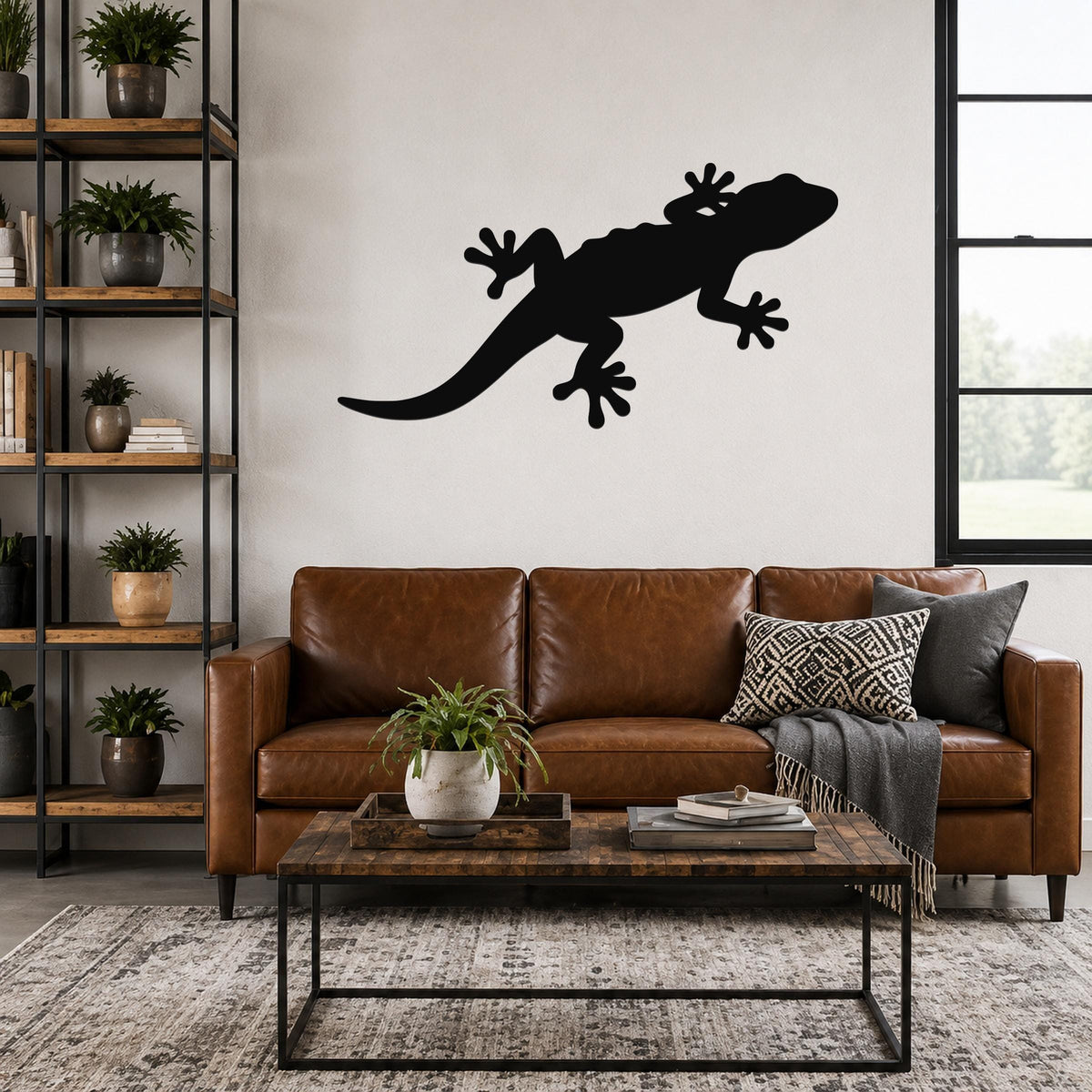 Black metal gecko wall art silhouette mounted above a brown leather sofa in a living room.