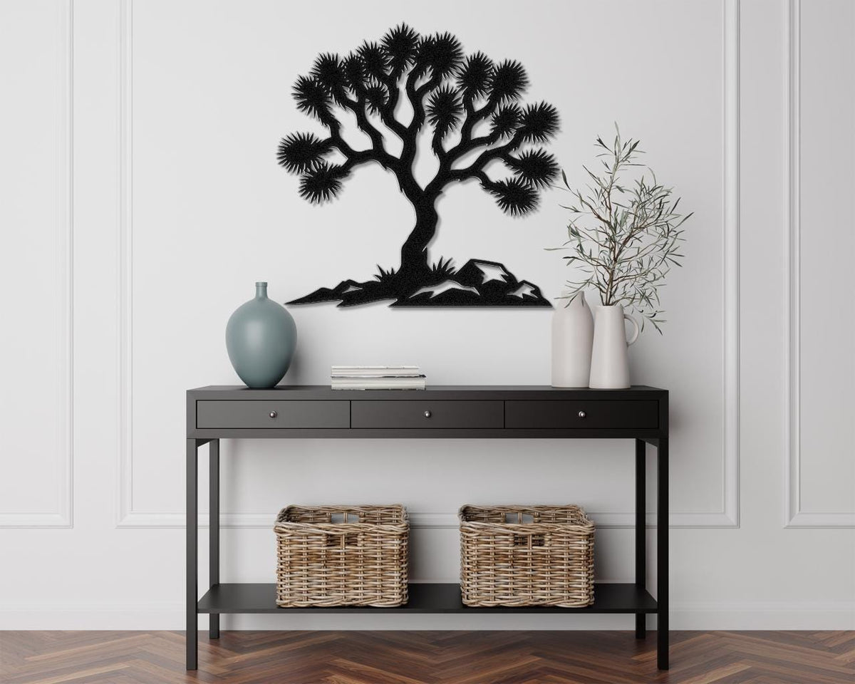 Black metal wall art featuring a Joshua tree silhouette with spiky branches and mountain base, mounted above a console table in a living room.