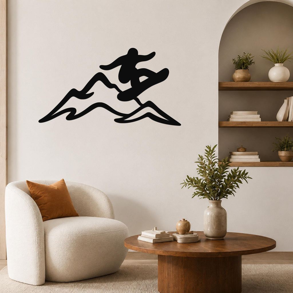 Black metal wall art silhouette of a snowboarder in motion over mountain waves, mounted on a living room wall above a white armchair.