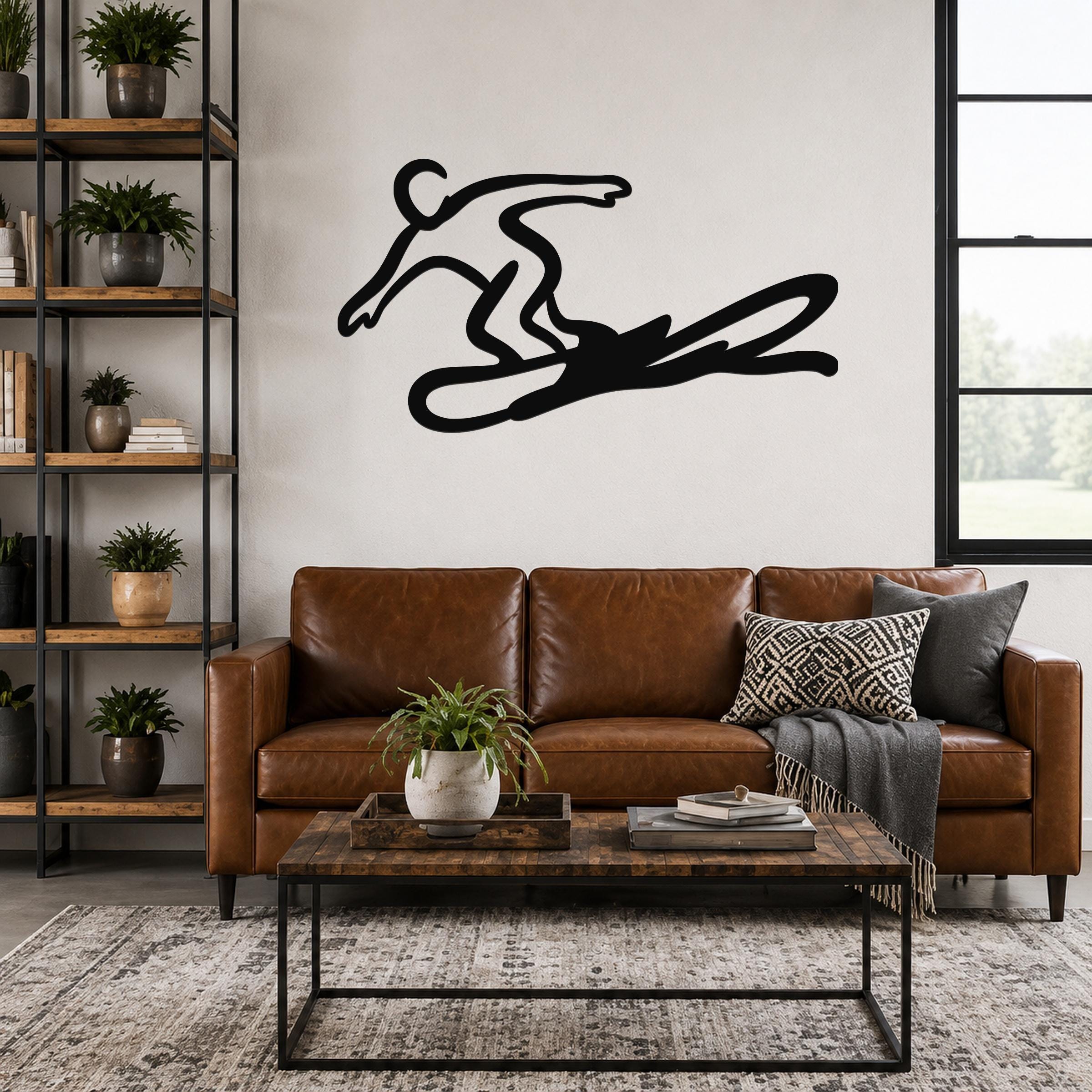 Black metal wall art silhouette of a snowboarder in motion, mounted above a brown leather sofa in a living room.