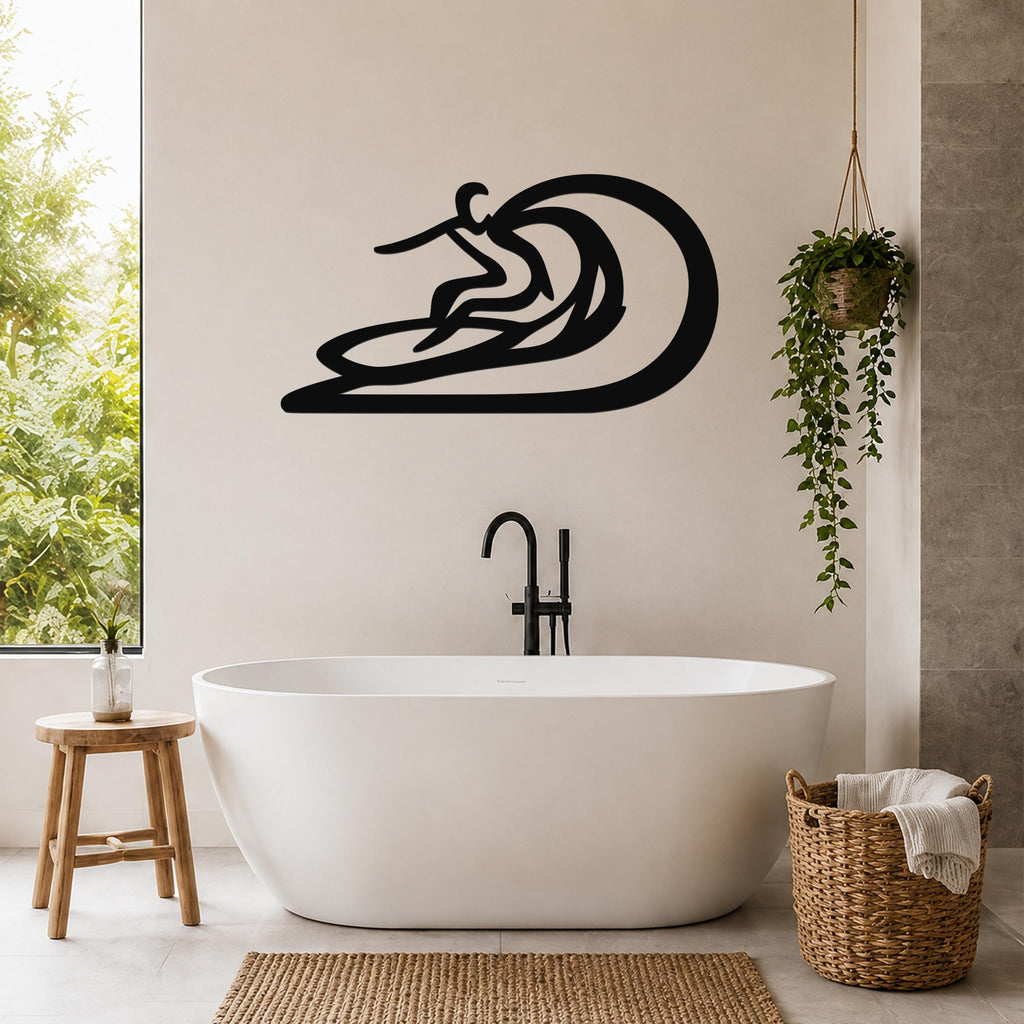 Black metal surfer wall sculpture with wave cutout, mounted on a bathroom wall above a freestanding tub.