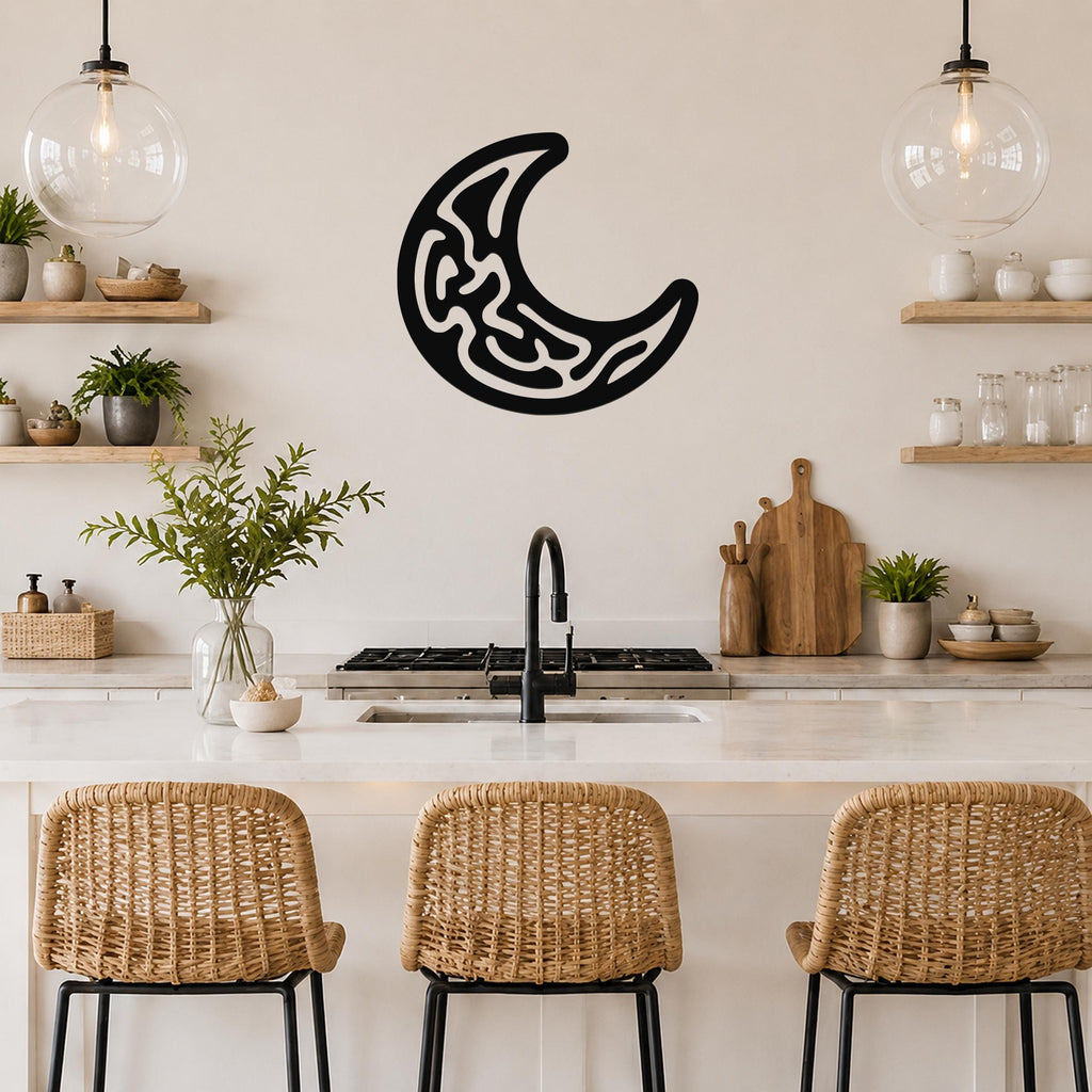 Black metal crescent moon wall art with intricate internal cutouts, mounted on a kitchen wall above a counter.