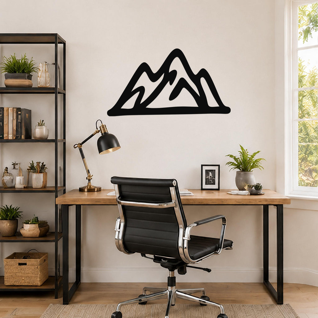 Black metal mountain silhouette wall art with layered peaks, mounted above a wooden desk in a home office.