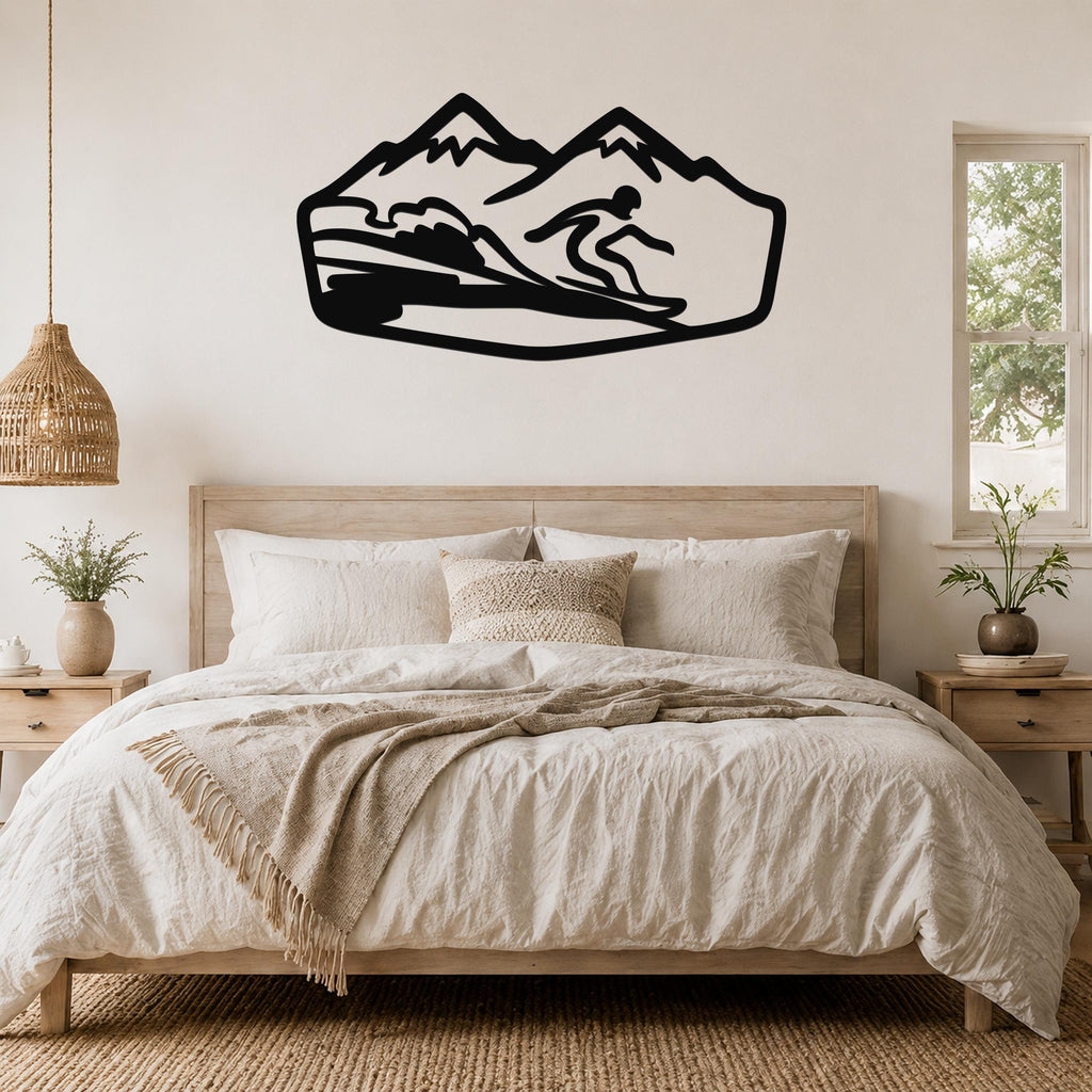 Black metal wall art silhouette of a snowboarder in motion on a mountain slope, mounted above a bed in a bedroom.
