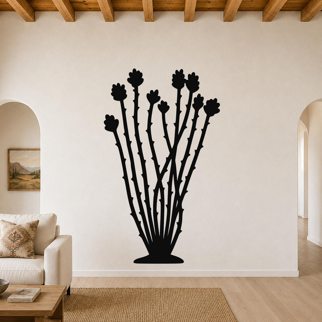Black metal ocotillo wall art with spiny stems and flower cutouts, mounted on a living room wall above a sofa.