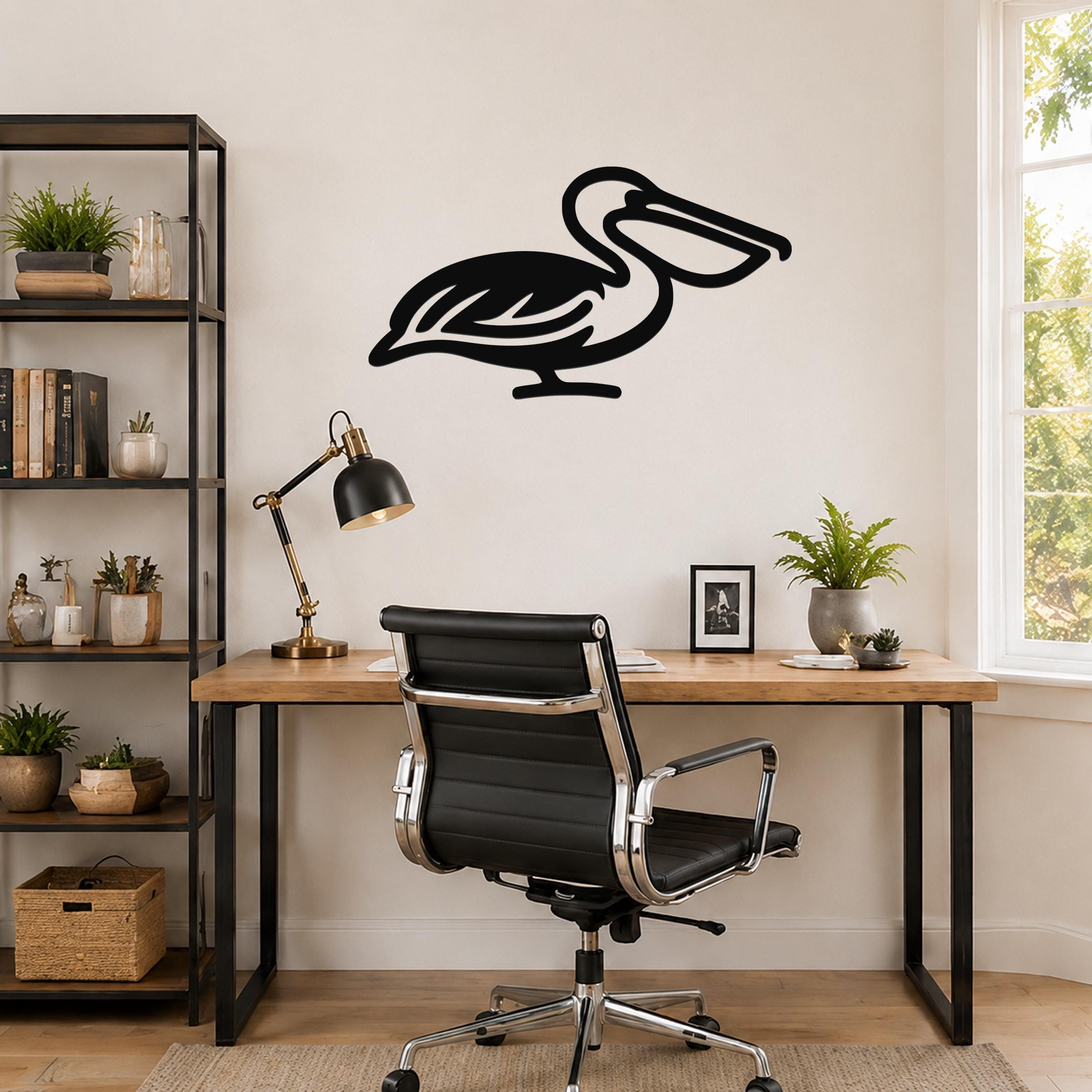 Black metal pelican wall art with internal cutout details, mounted on a wall above a wooden desk in a home office.