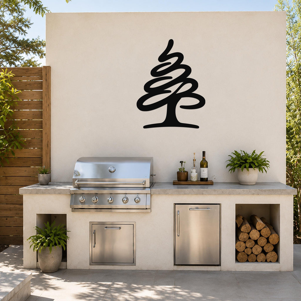 Black metal pine tree wall art silhouette mounted on a light-colored outdoor wall above a kitchen counter with a grill and storage.