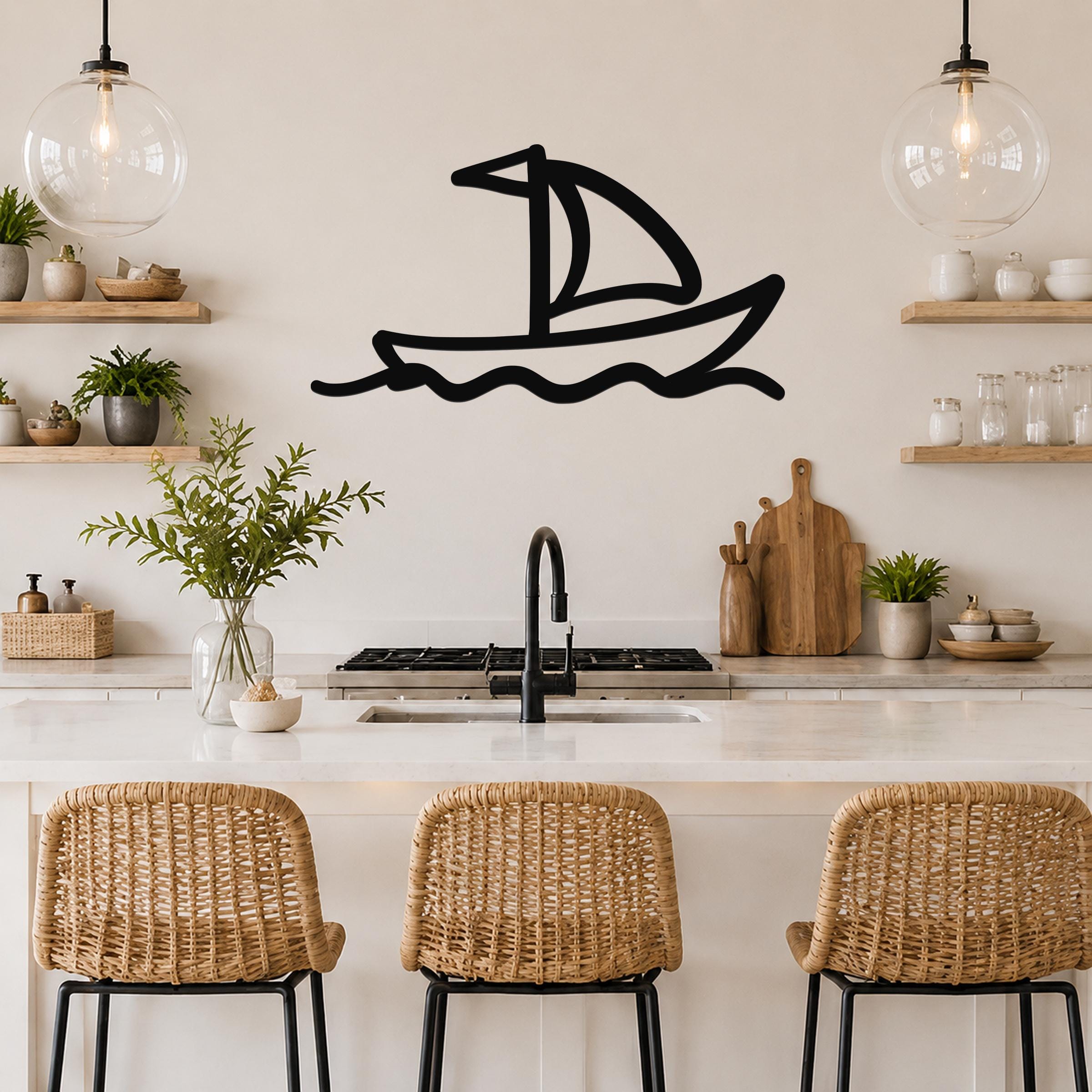 Black metal sailboat wall art with wavy water lines, mounted on a kitchen wall above a counter.