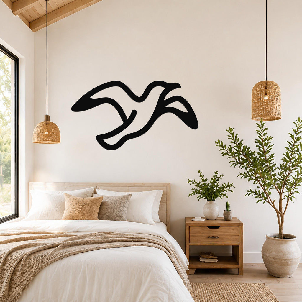 Black metal seagull wall art with flowing motion lines, mounted above a bed in a bright bedroom.