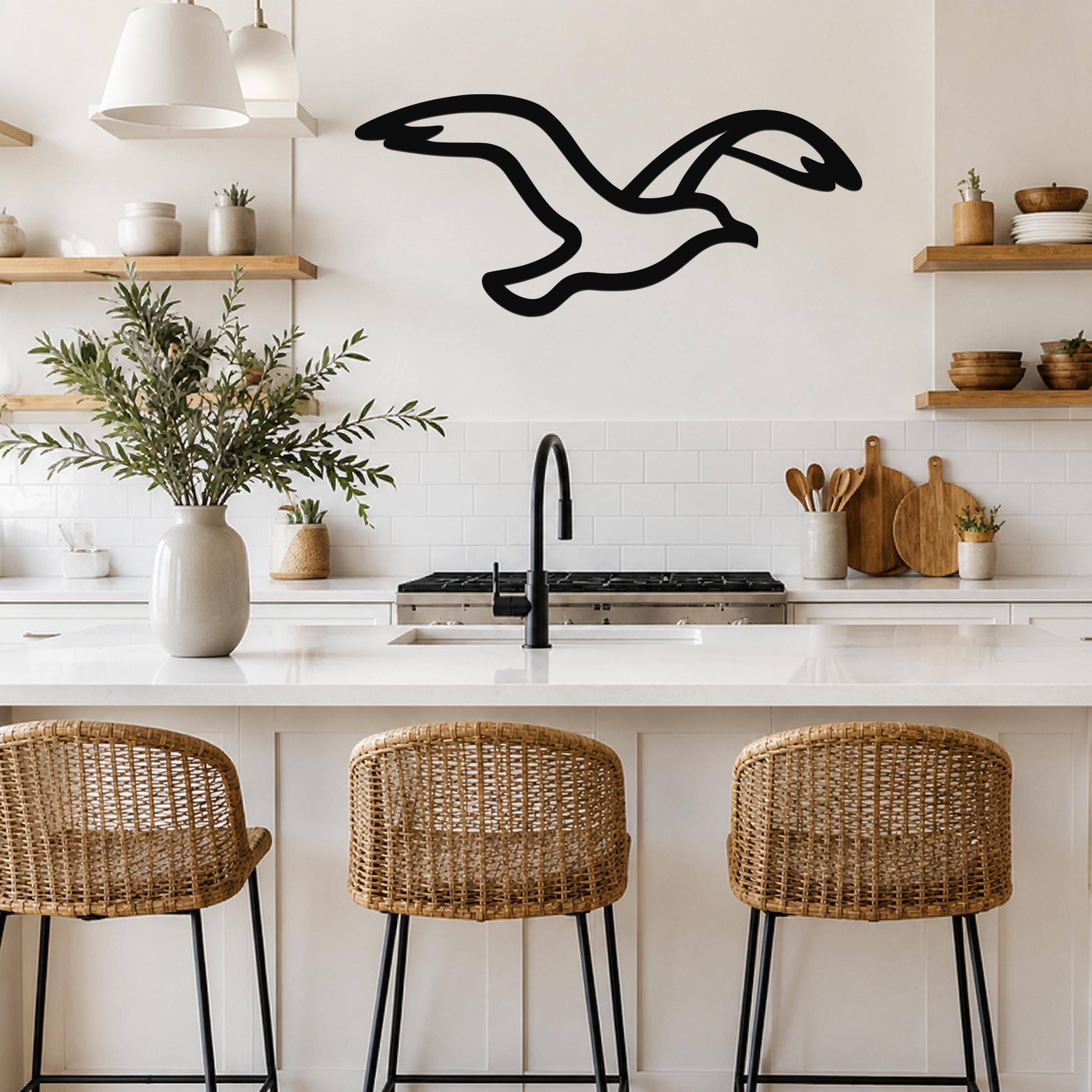 Black metal seagull wall art with motion-line cutouts, mounted above a kitchen counter in a bright, modern kitchen.