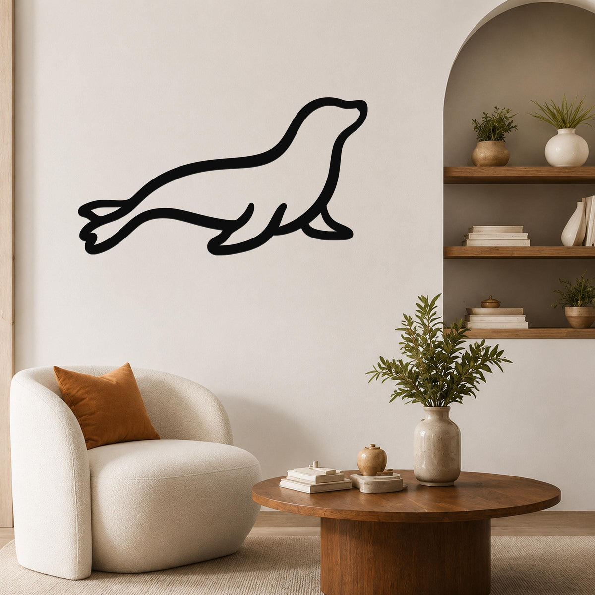 Black metal sea lion wall art in a silhouette style, mounted on a living room wall above a round wooden coffee table.