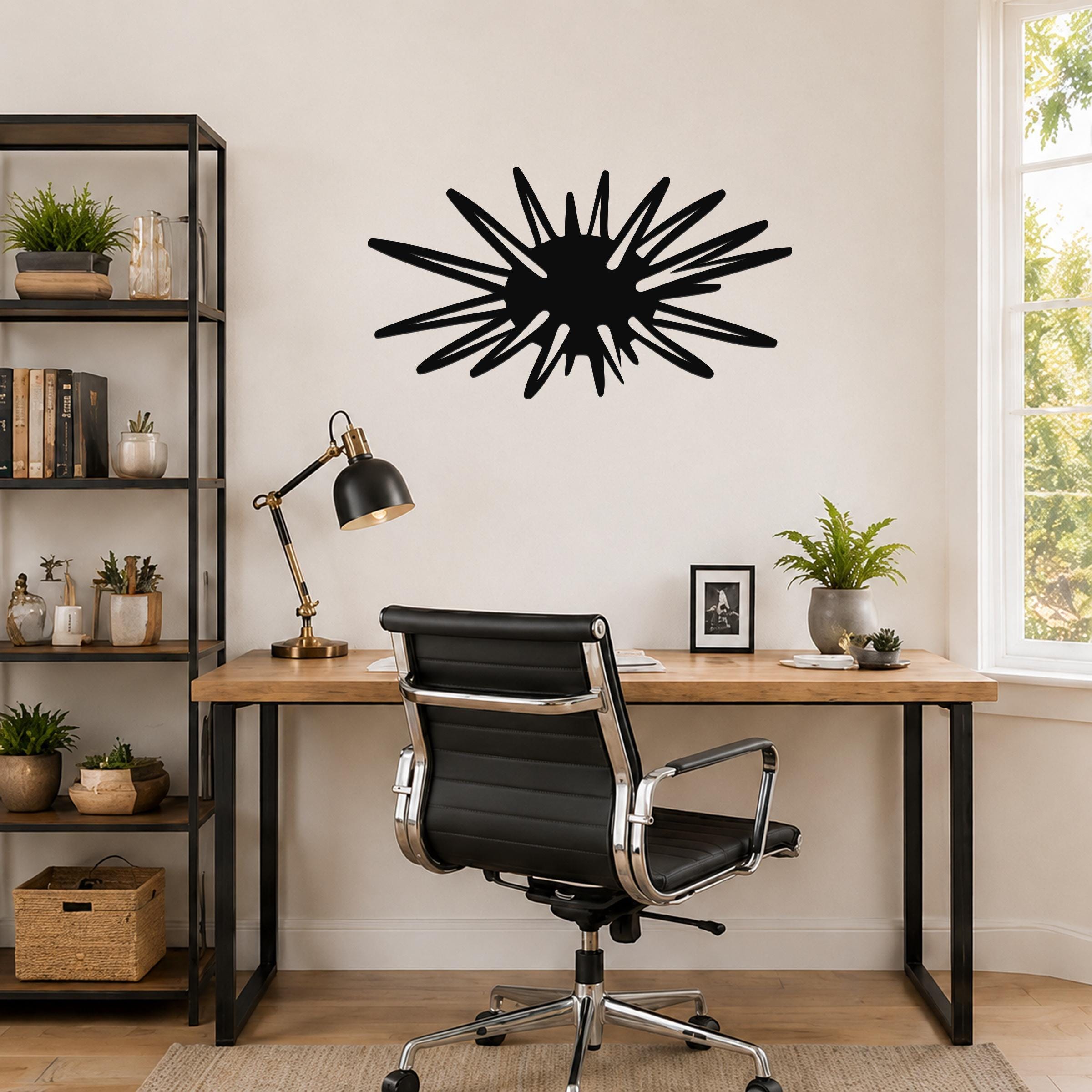 Black metal wall art in a sea urchin silhouette with radiating spines, mounted on a wall above a wooden desk in a home office.