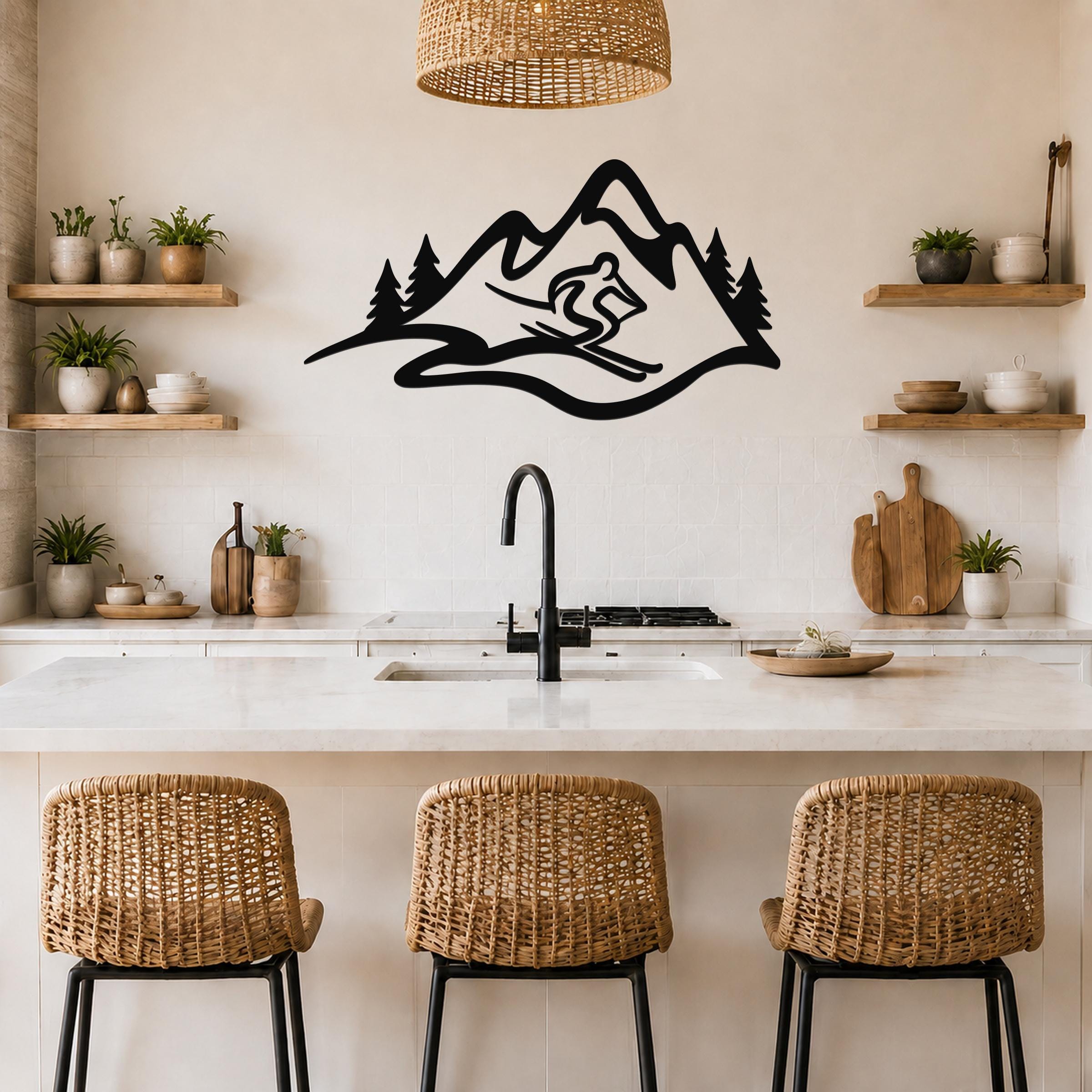 Black metal wall art featuring a skier silhouette descending a mountain with pine trees, mounted above a kitchen counter.