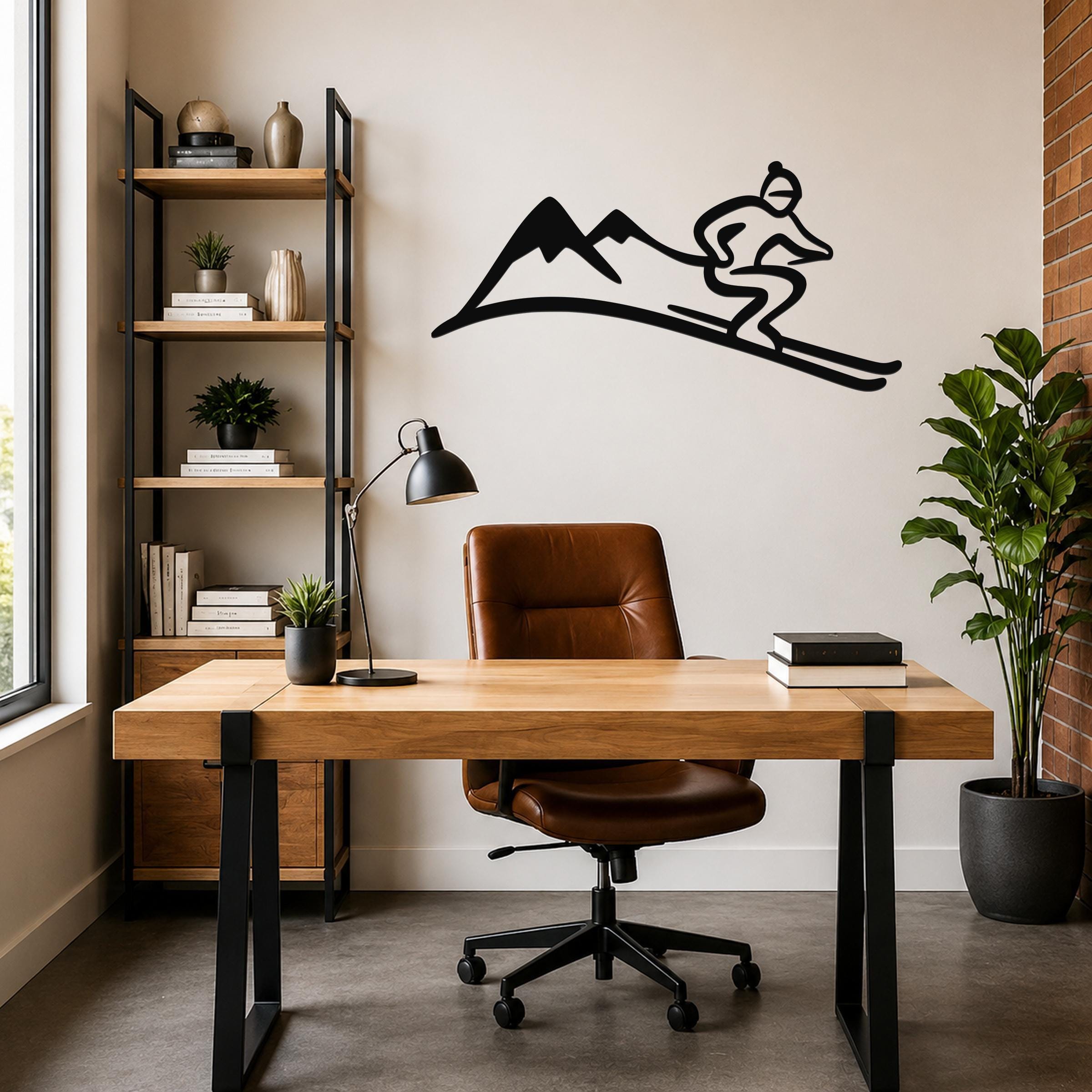 Black metal skier and mountain wall art silhouette mounted above a wooden desk in a modern home office.