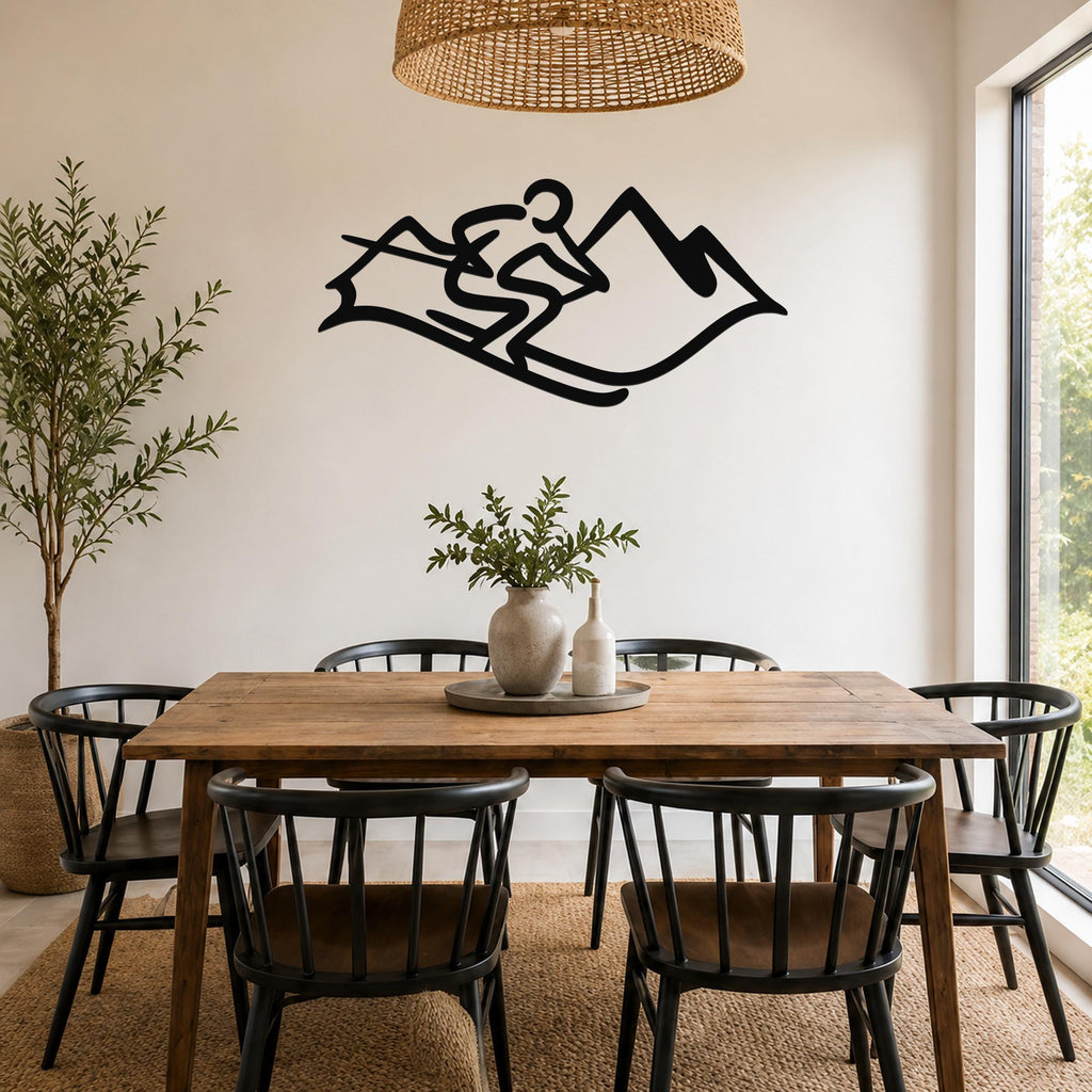 Black metal wall art silhouette of a skier on a mountain slope, mounted above a wooden dining table in a bright dining room.