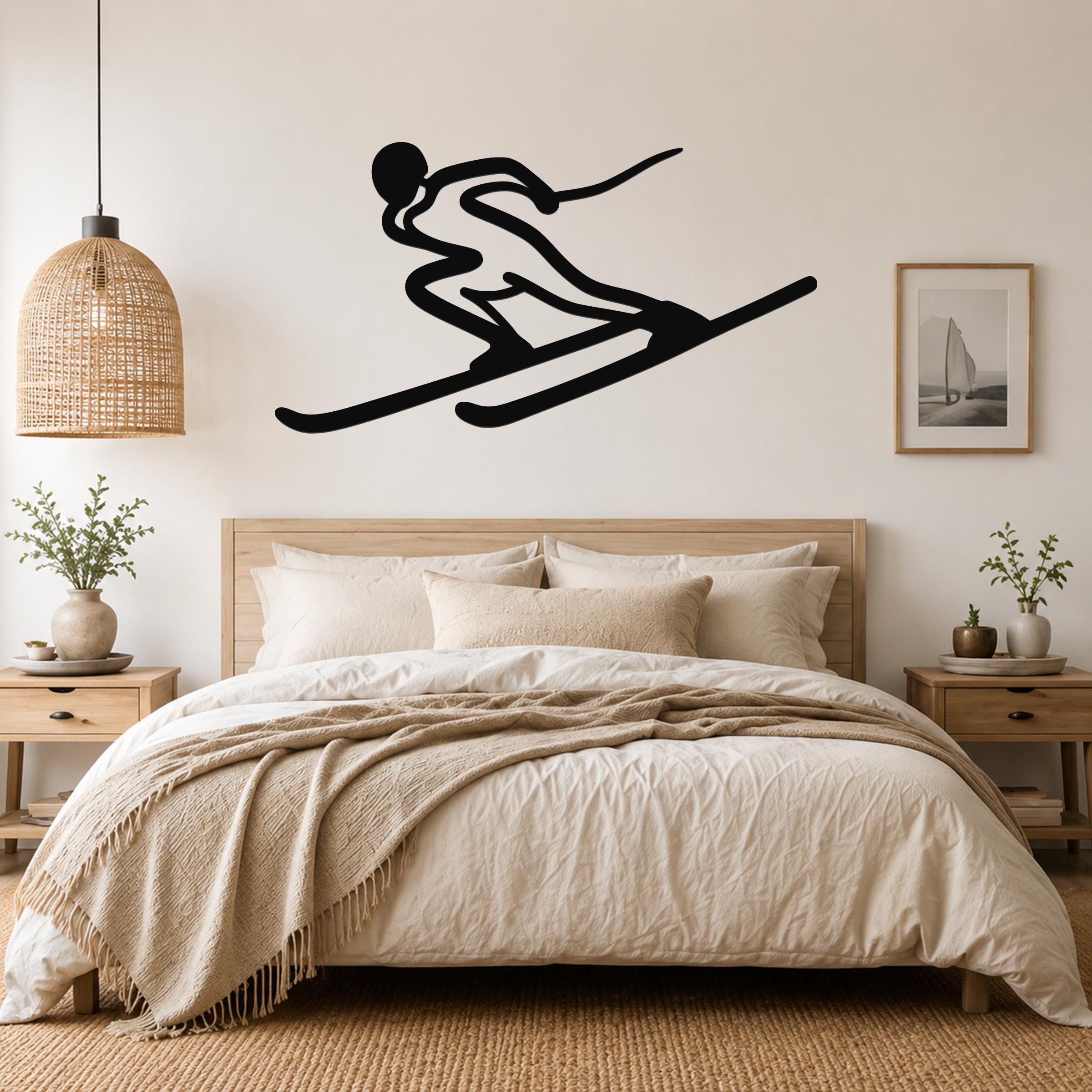 Black metal skier silhouette wall art with motion lines, mounted above a bed in a neutral bedroom.